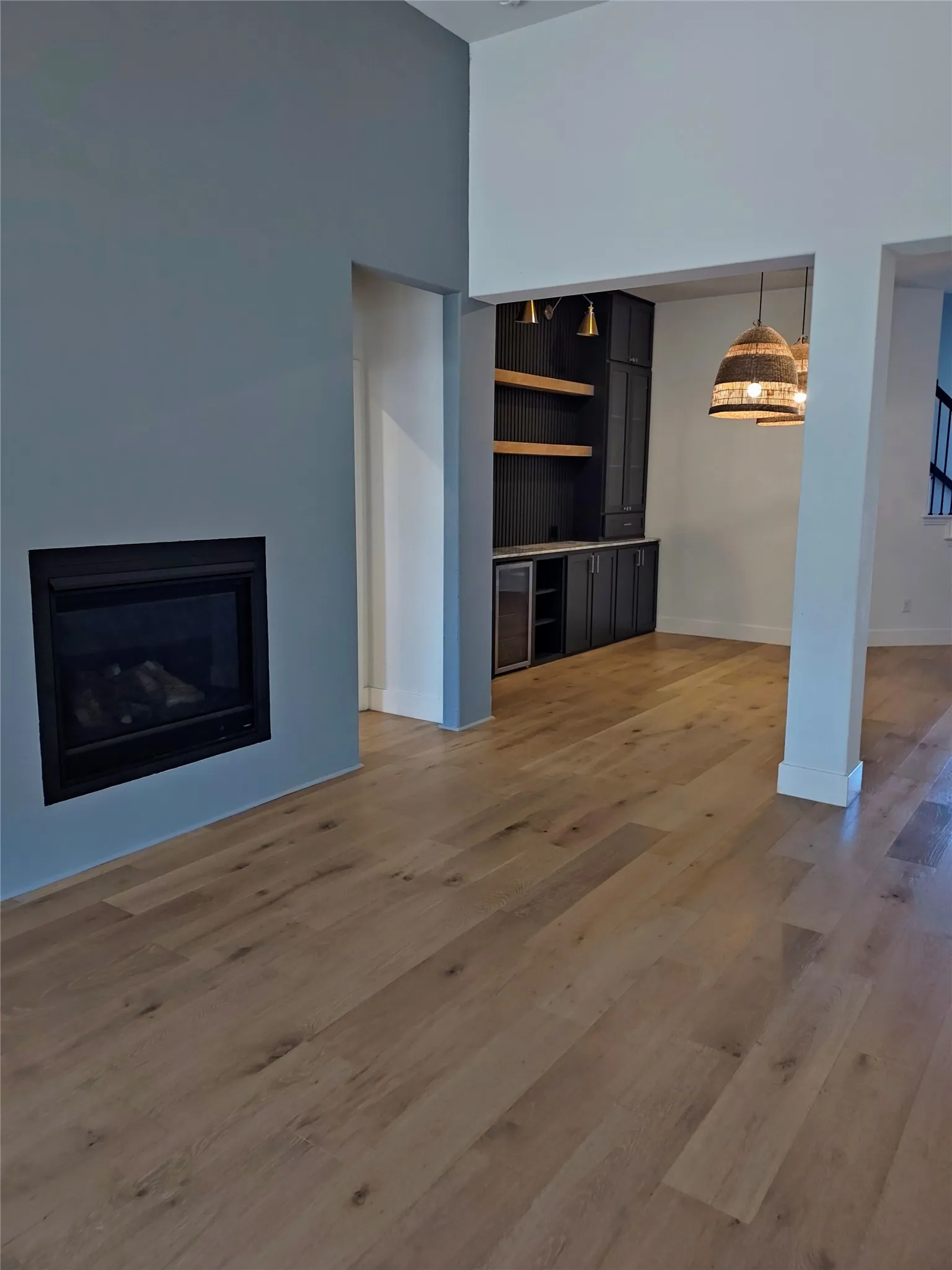 Wood-finish flooring throughout, built-in fireplace, built-in cabinetry with open shelving, and integrated beverage cooler