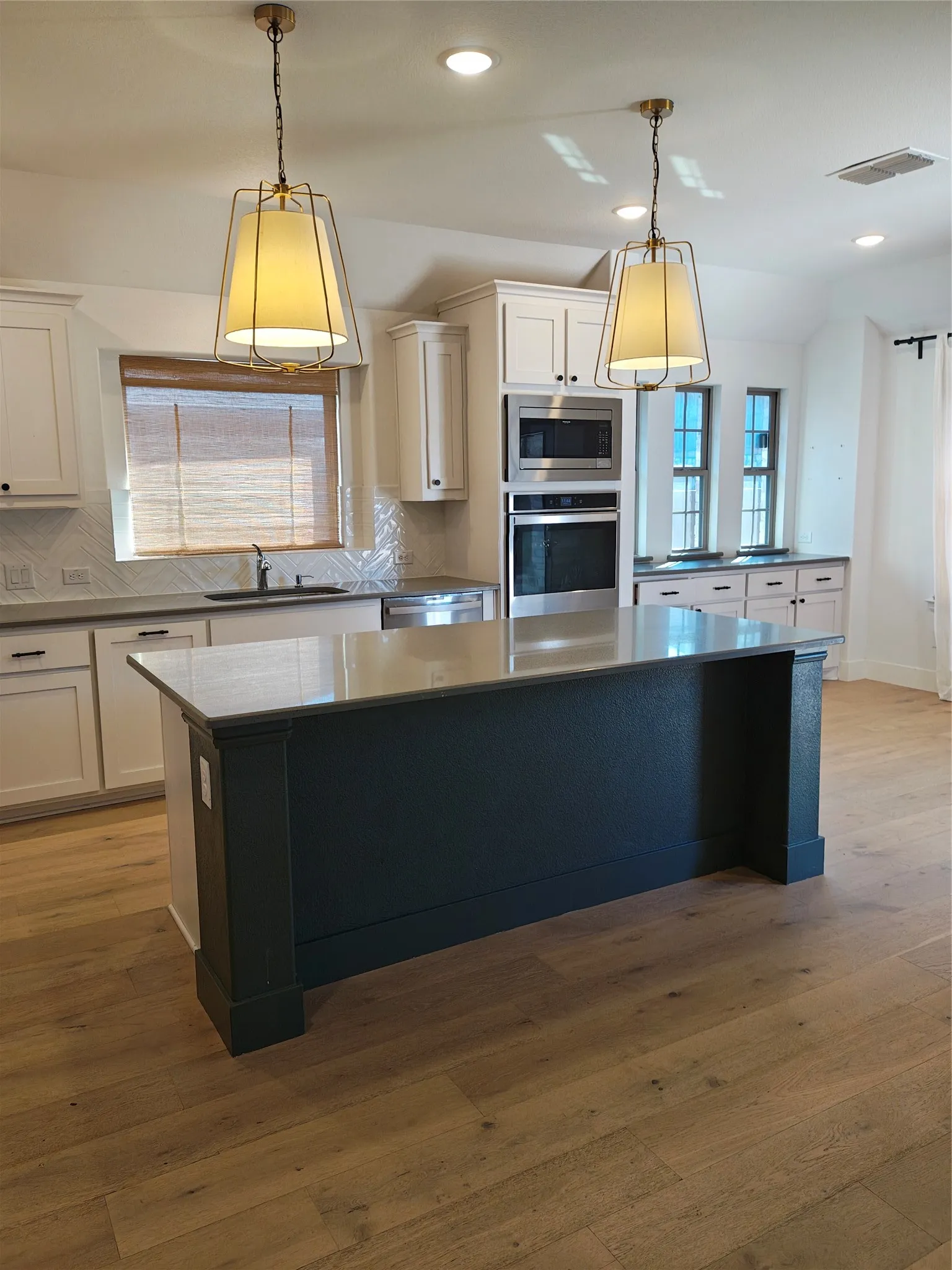Kitchen featuring a central island with a contrasting base, wood-finish flooring, recessed lighting, and pendant light fixtures