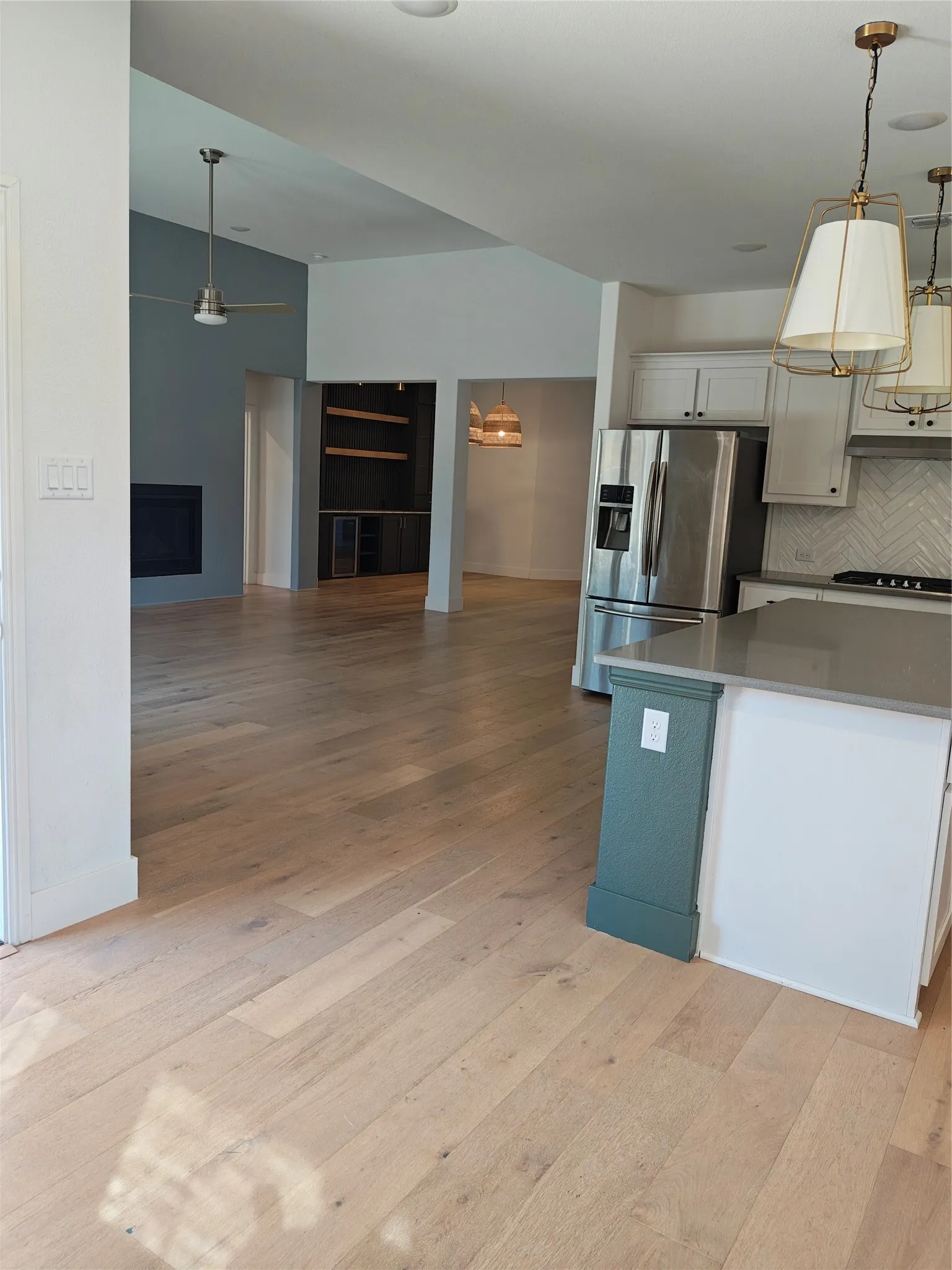 Vaulted ceilings, light wood-finish flooring, recessed lighting, and a stainless steel refrigerator