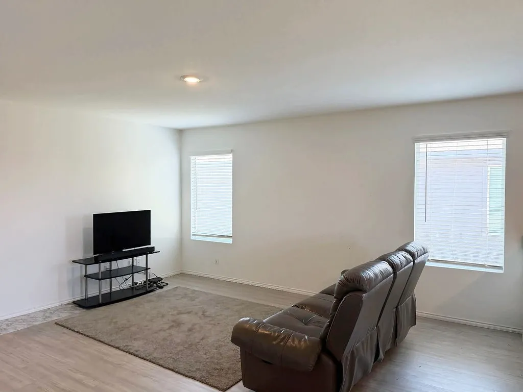 Spacious room featuring light wood-finish flooring, neutral wall tones, and recessed ceiling lighting