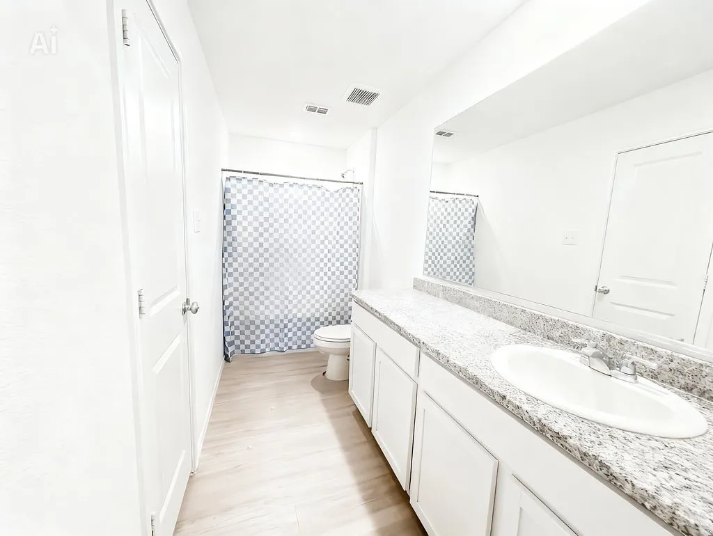 Bathroom featuring a double vanity with stone countertops, white cabinetry, and a large mirror