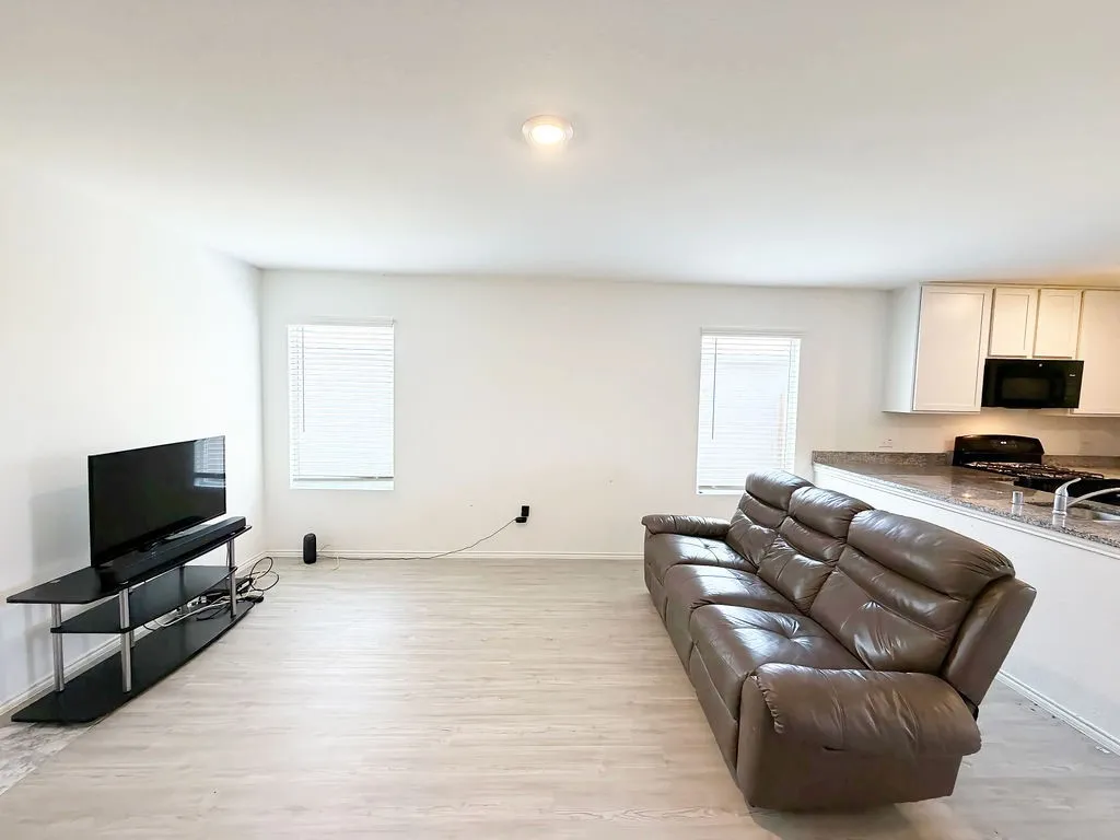 Open-concept living space featuring wood-finish flooring, recessed ceiling lighting, and white walls