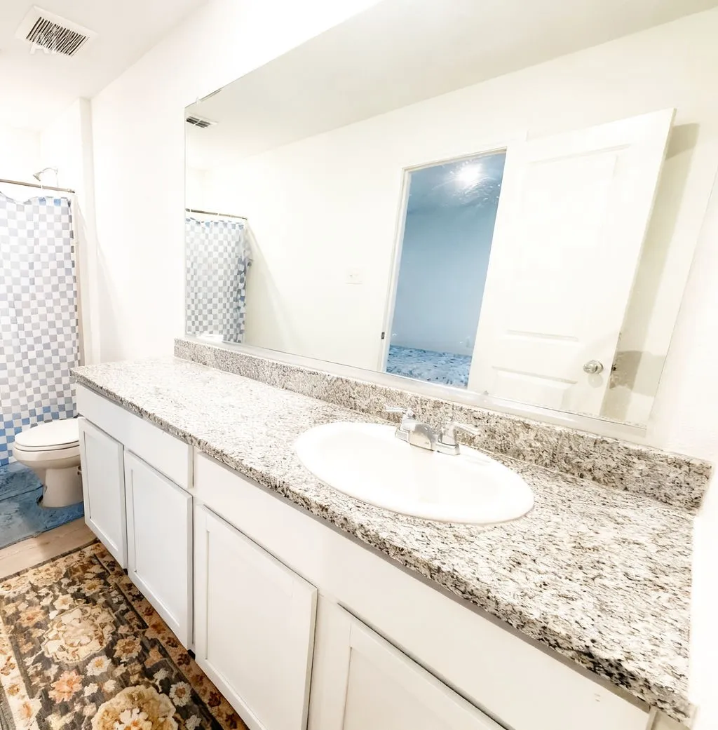 Bathroom featuring a wide vanity with a granite countertop, undermount sink, and chrome faucet