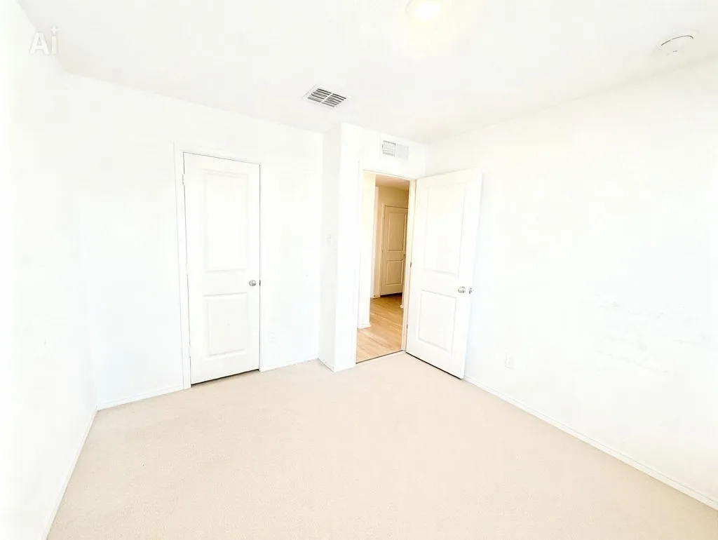 Room with light-colored carpeting, white walls, and white trim