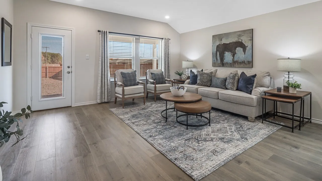 Spacious living area featuring wood-finish flooring, vaulted ceilings, and a neutral color palette