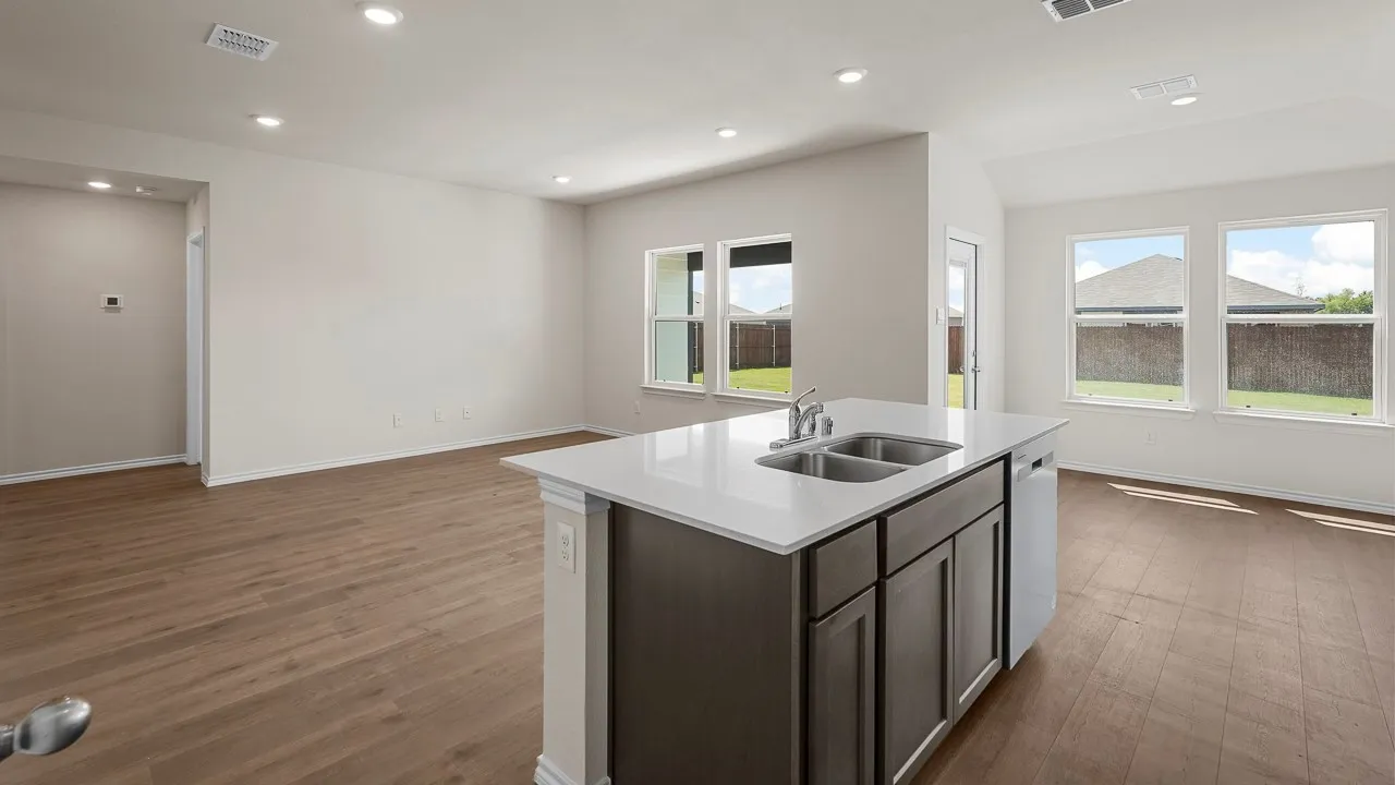 Central kitchen island featuring a double-basin stainless steel sink, integrated dishwasher, and a light-toned countertop
