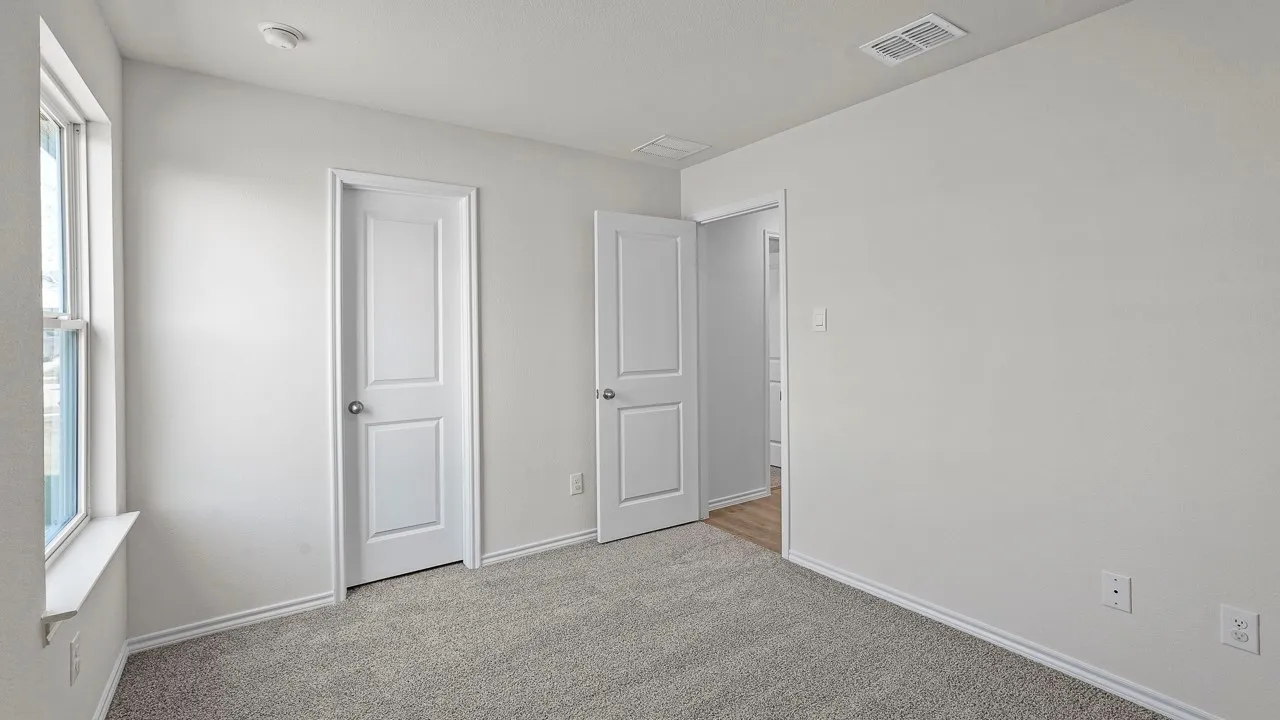 Light gray carpeted room with white walls, baseboards, and window trim