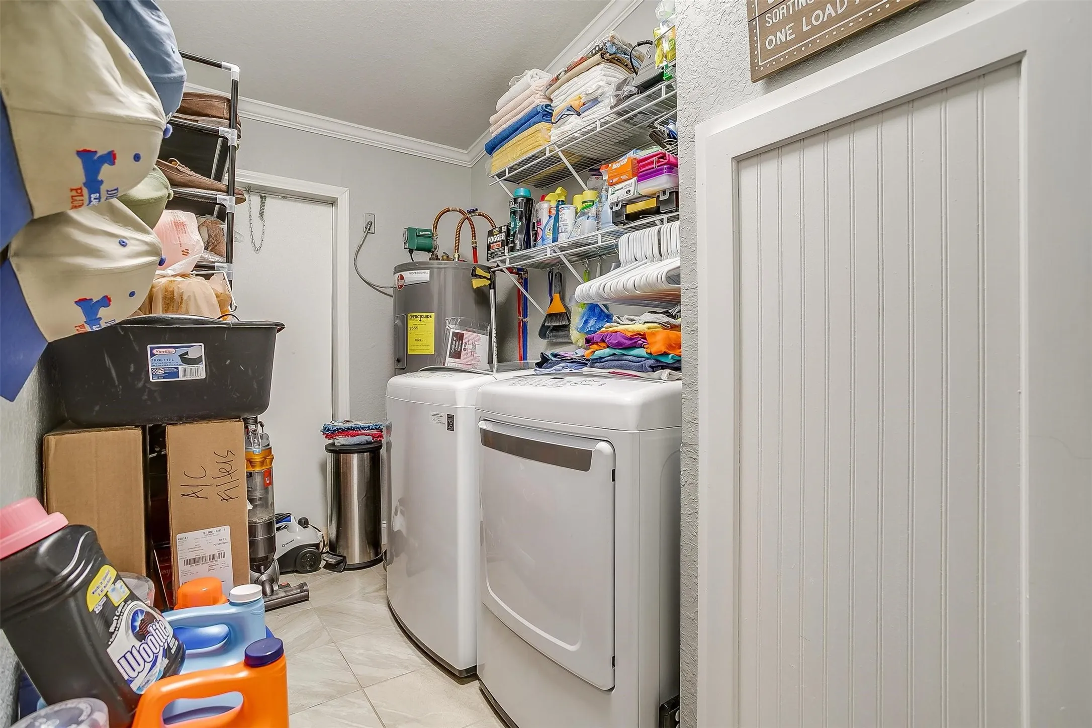 Laundry area featuring tile flooring, white walls, and crown molding