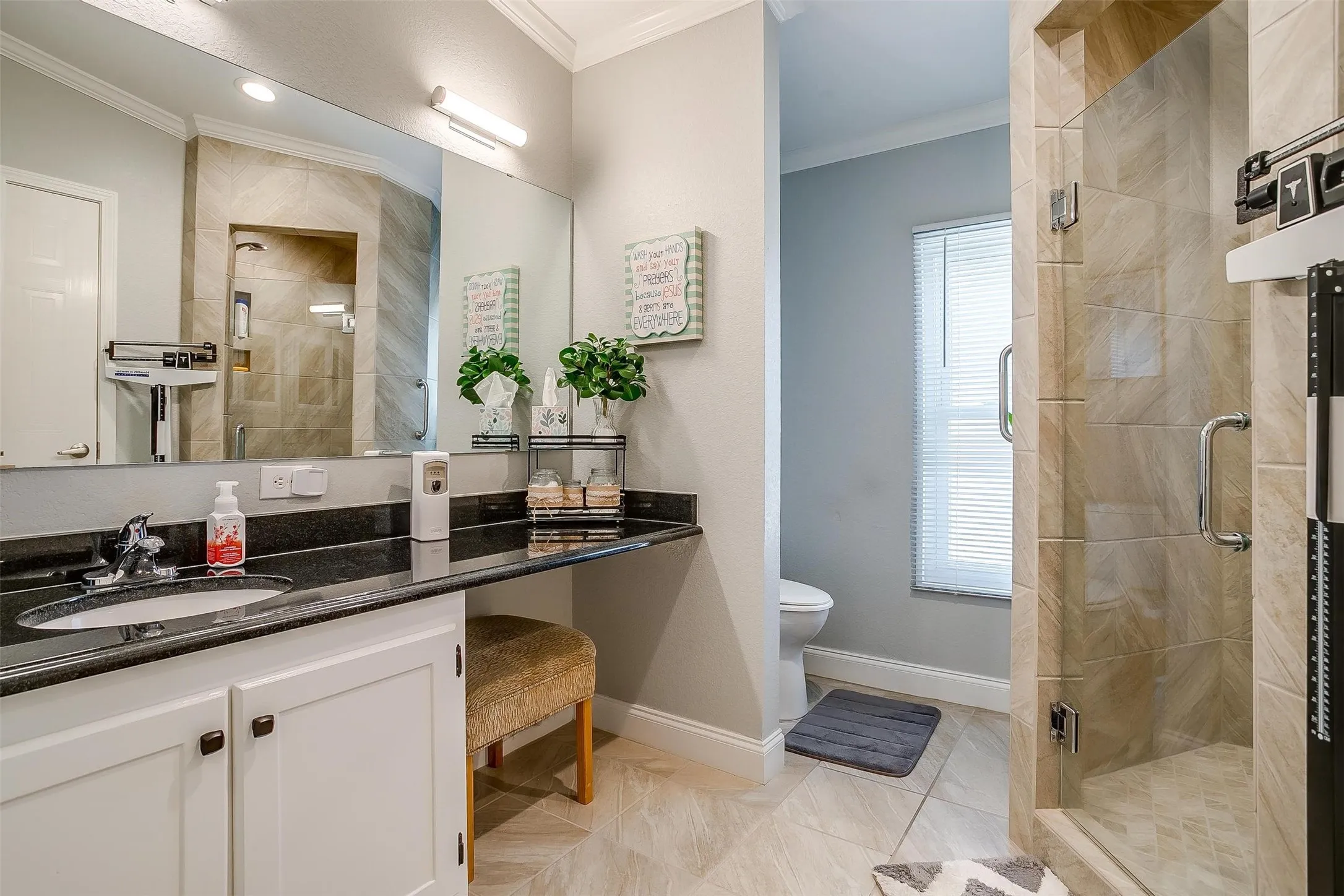 Bathroom featuring a glass-enclosed shower with tile surround, a single vanity with dark countertop and undermount sink, white cabinetry, and a large wall-mounted mirror