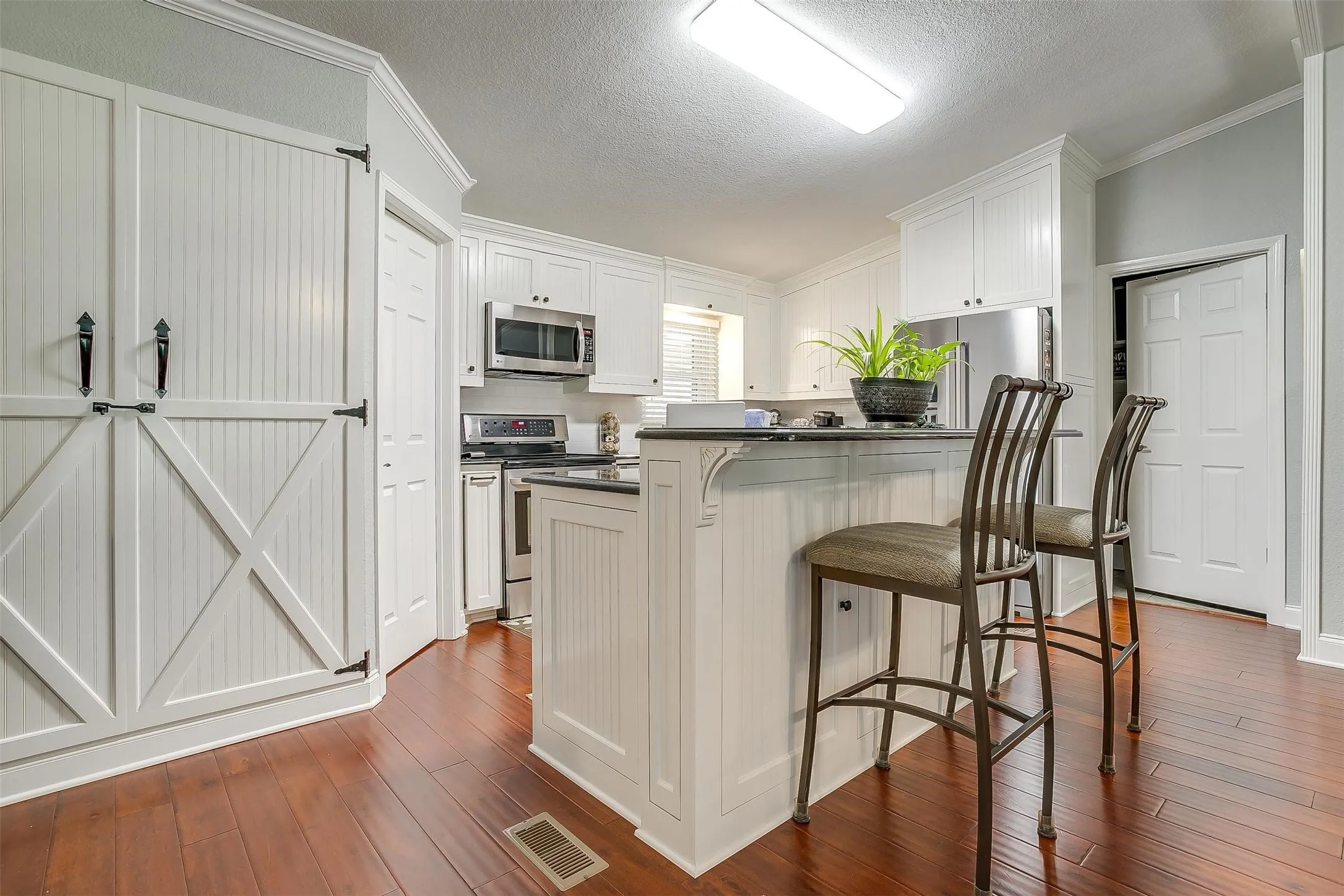Kitchen featuring a central island with counter seating, white cabinetry, dark countertops, and stainless steel appliances