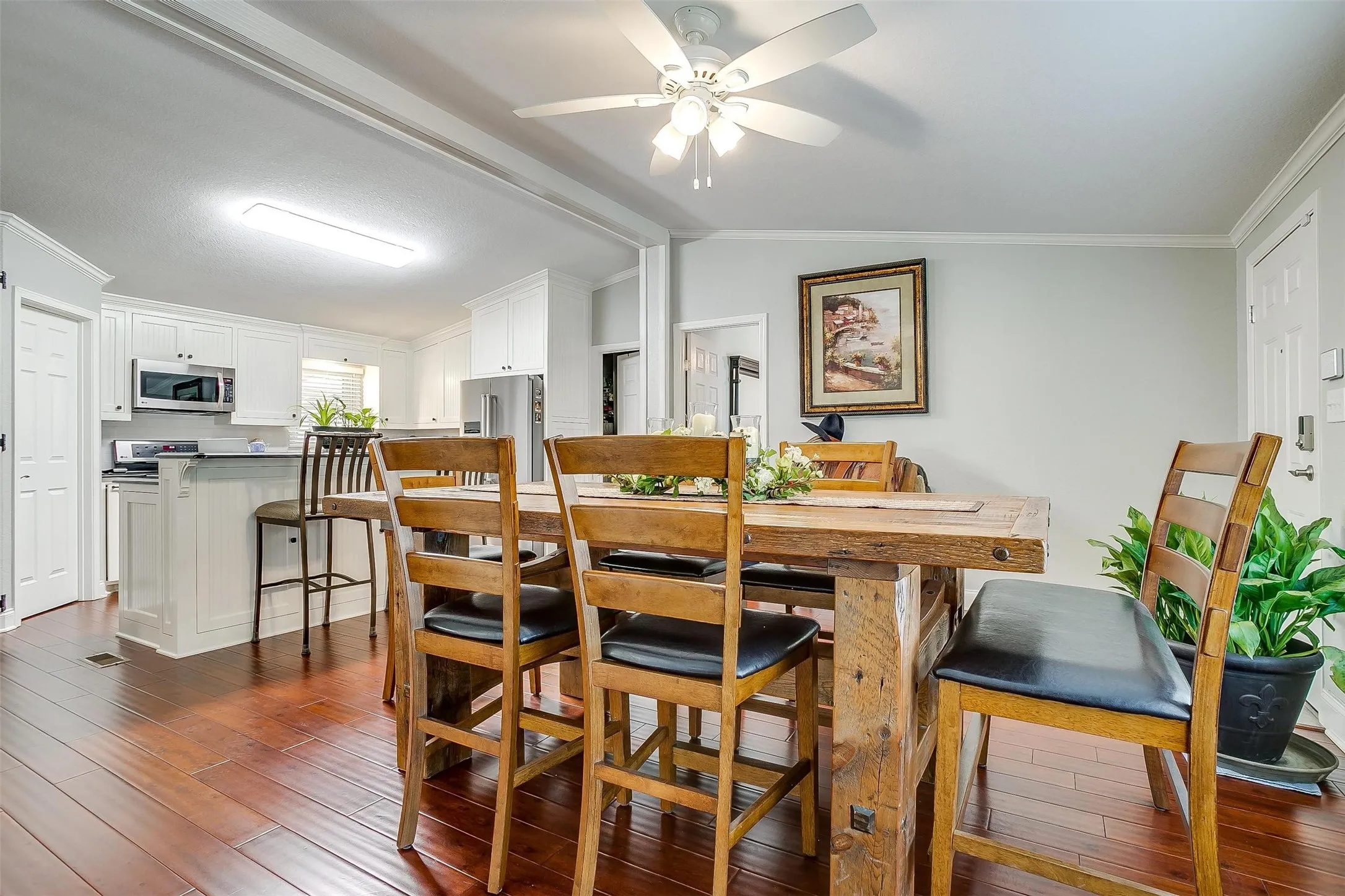 Open-concept dining area featuring wood-finish flooring, a ceiling fan, and white trim molding