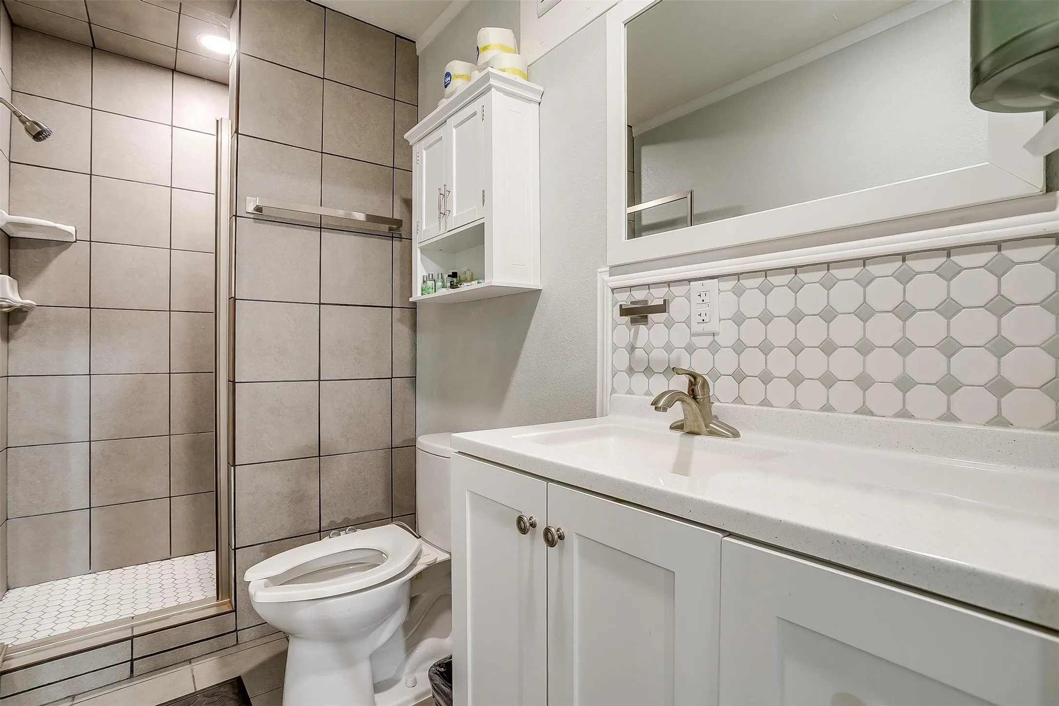 Bathroom featuring a shower with light grey square tiles and a white octagonal tile floor