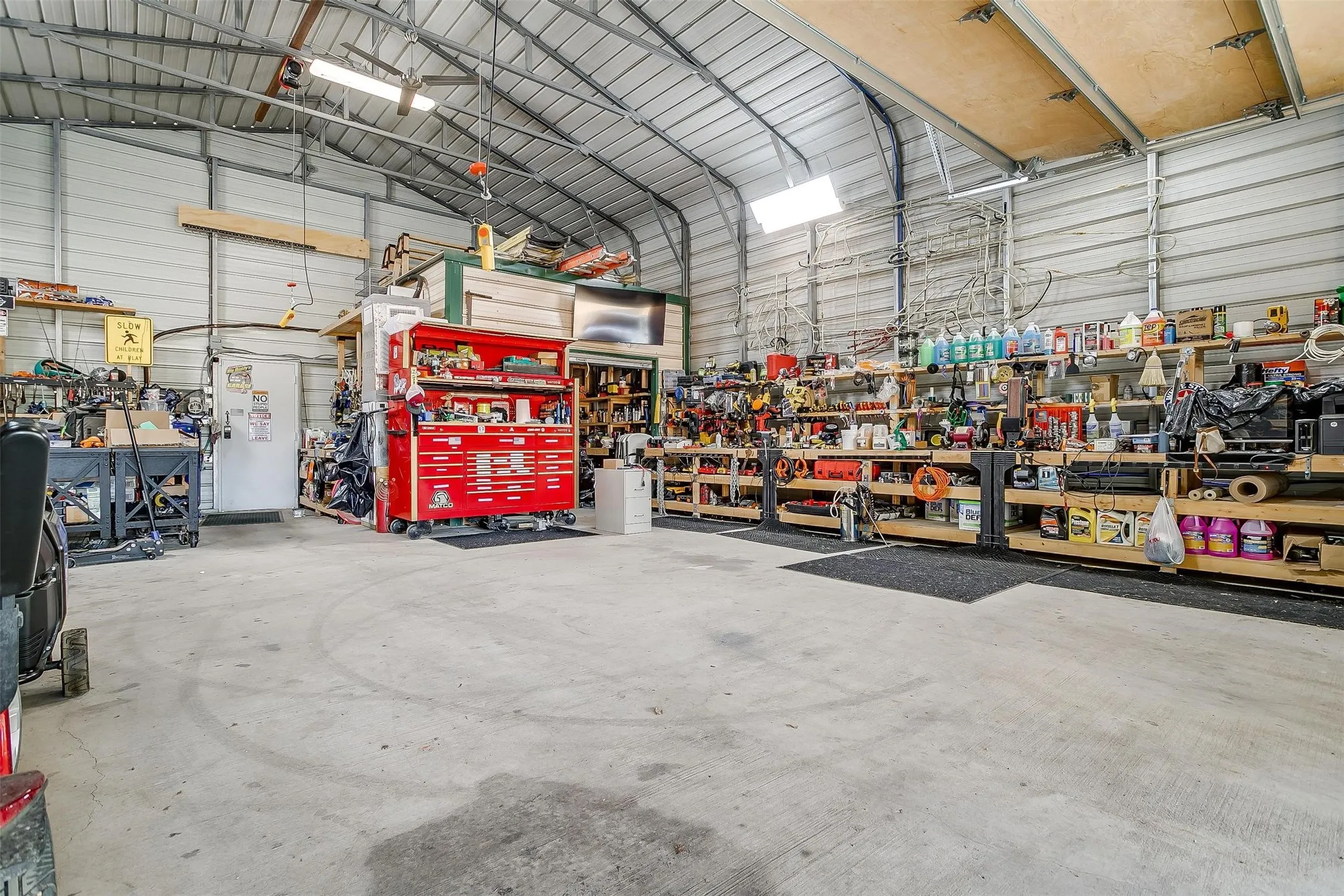 Spacious garage/workshop with a concrete floor and a metal vaulted ceiling