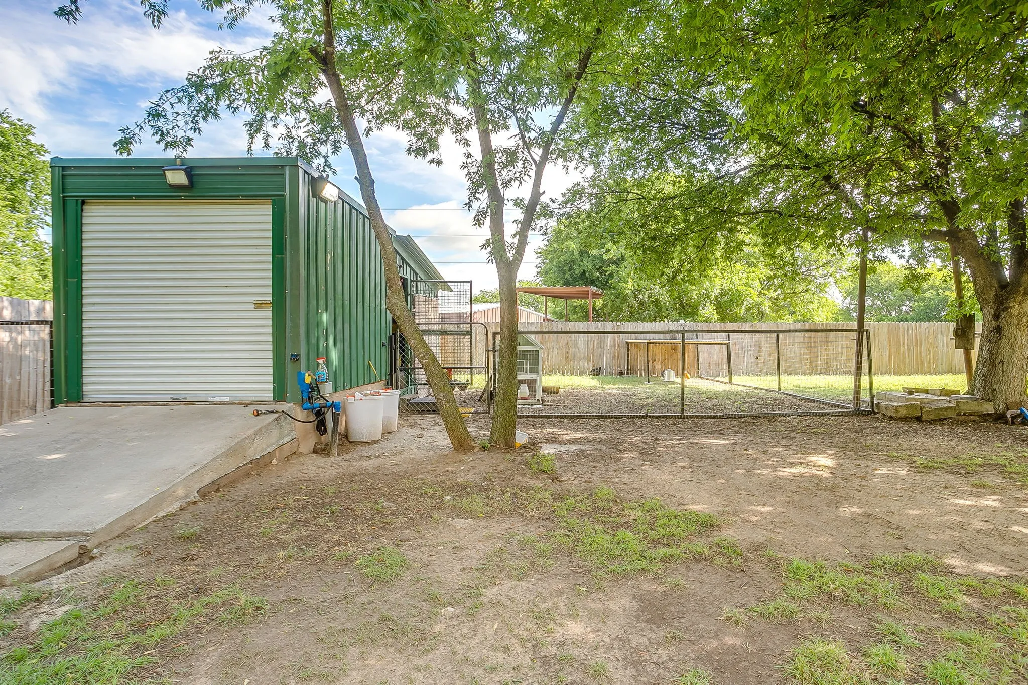 Metal outbuilding with a roll-up door, exterior lighting, and a concrete ramp