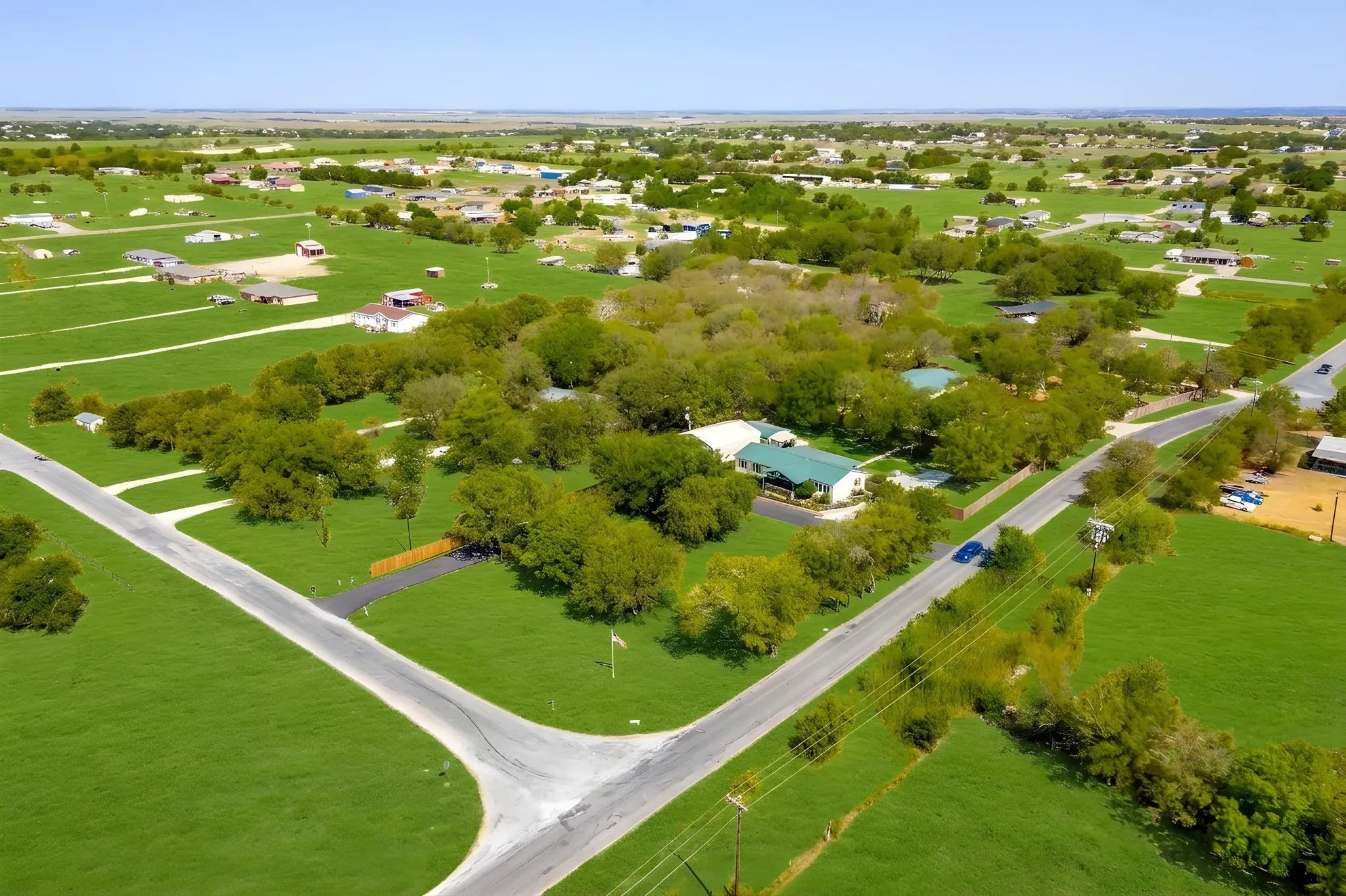 Expansive property featuring a verdant landscape, mature trees, and a visible road network