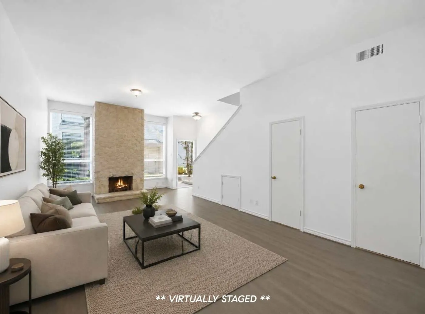 Living area featuring a stone-clad fireplace, wood-finish flooring, and bright windows