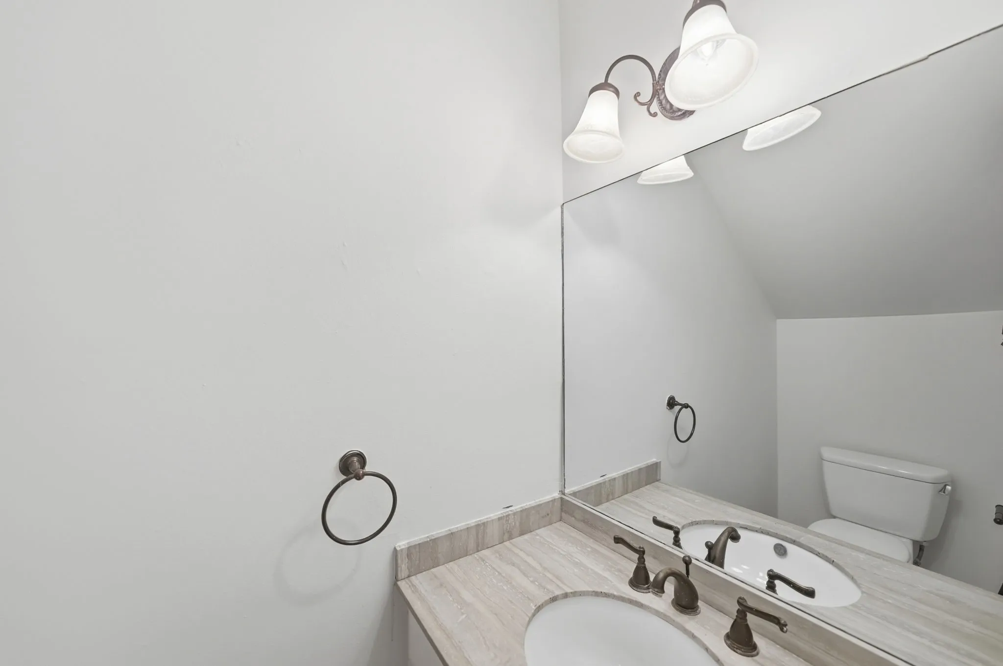 Bathroom vanity featuring a light-toned stone countertop, dual undermount sinks, and oil-rubbed bronze fixtures