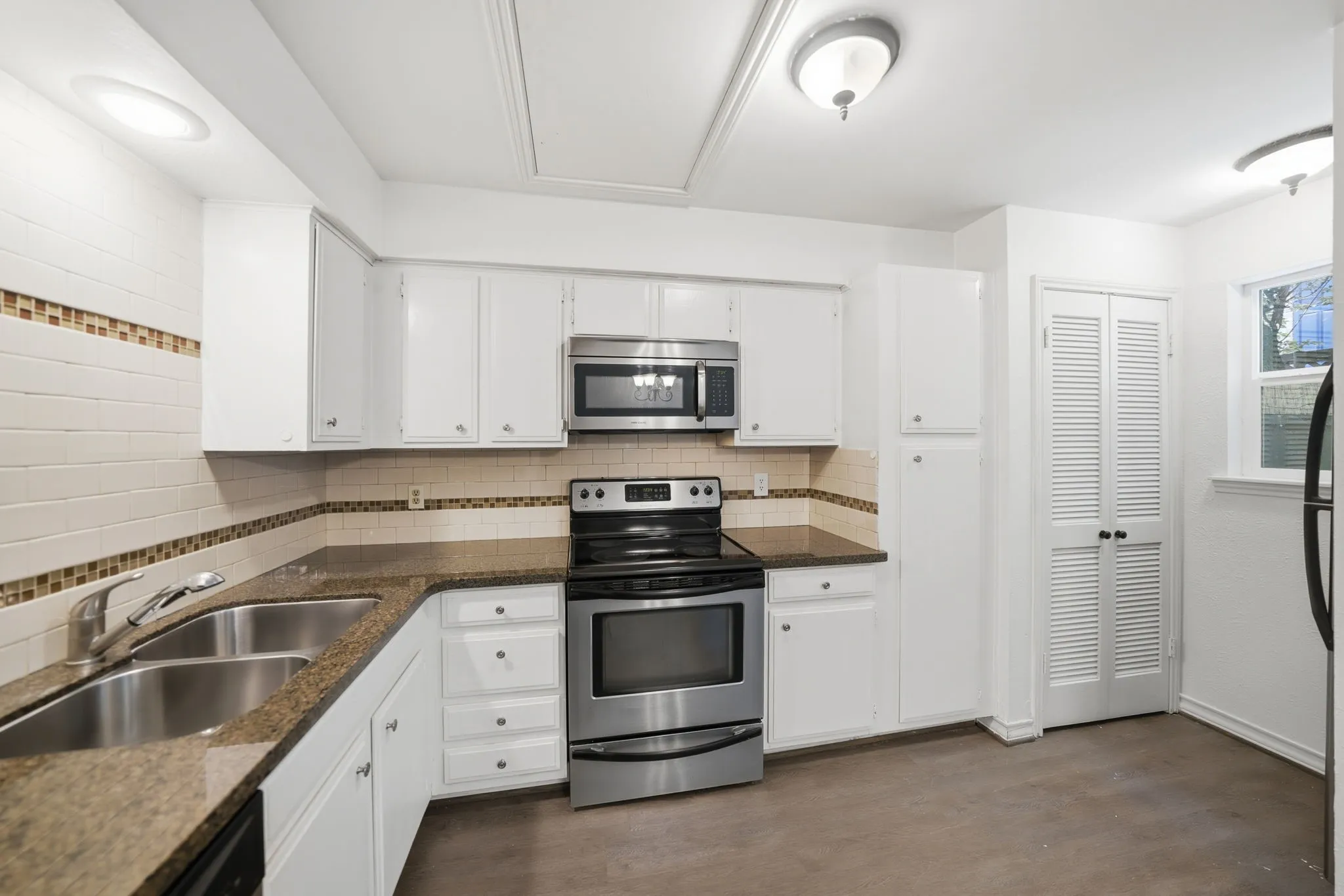 Kitchen featuring white cabinetry, stainless steel appliances, granite-style countertops, and a decorative tile backsplash