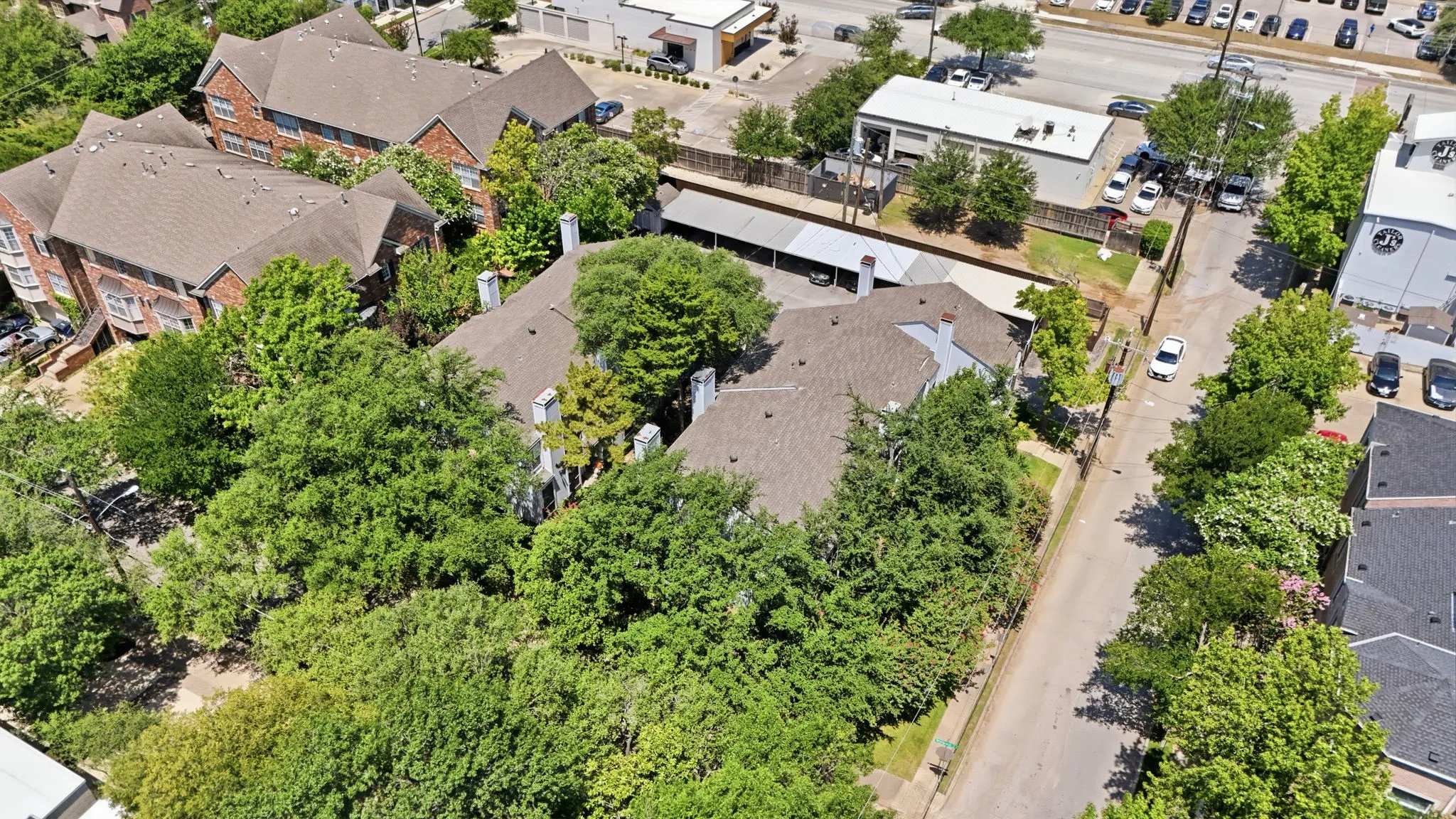Multi-building property with pitched shingle roofs and extensive tree coverage