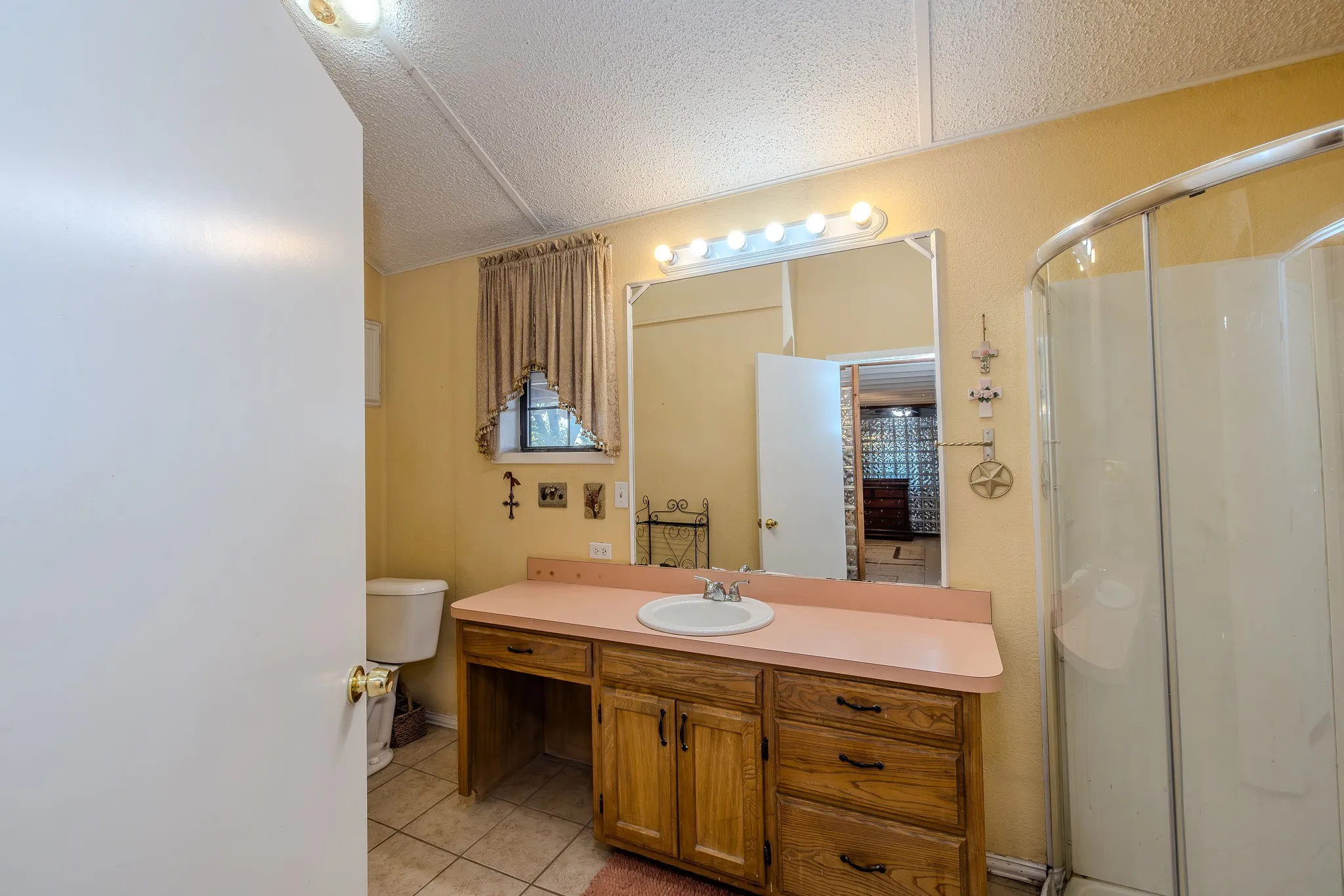 Spacious vanity and walk-in corner shower in the bathroom, with a window for natural ight.