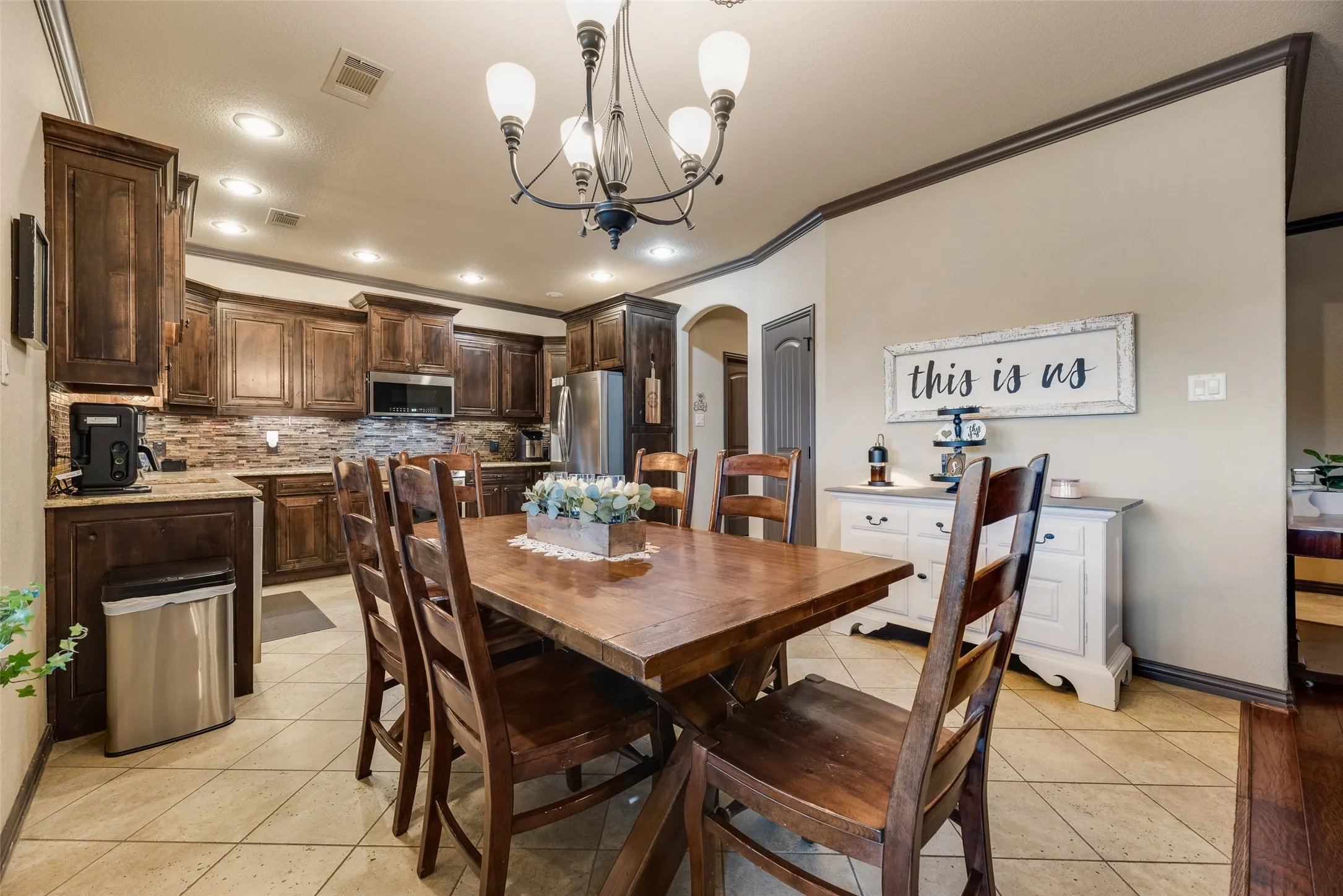 Open-concept kitchen and dining area featuring dark wood cabinetry, granite countertops, and a stone-finish backsplash