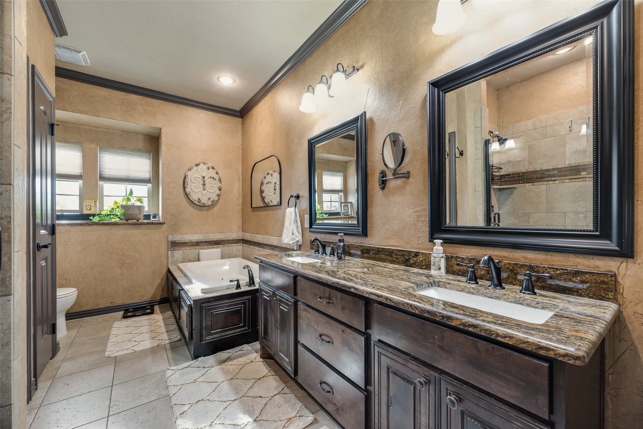Bathroom featuring a jetted soaking tub, dual vanity with undermount sinks, and a walk-in shower with tile surround