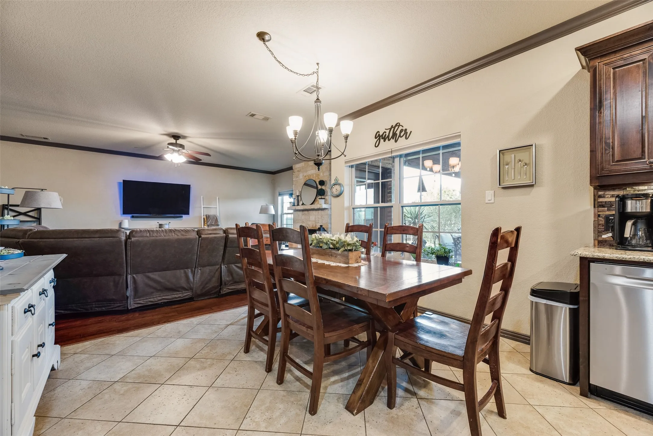 Open-concept dining and living area featuring tile flooring, a dark wood dining table, and a contemporary chandelier