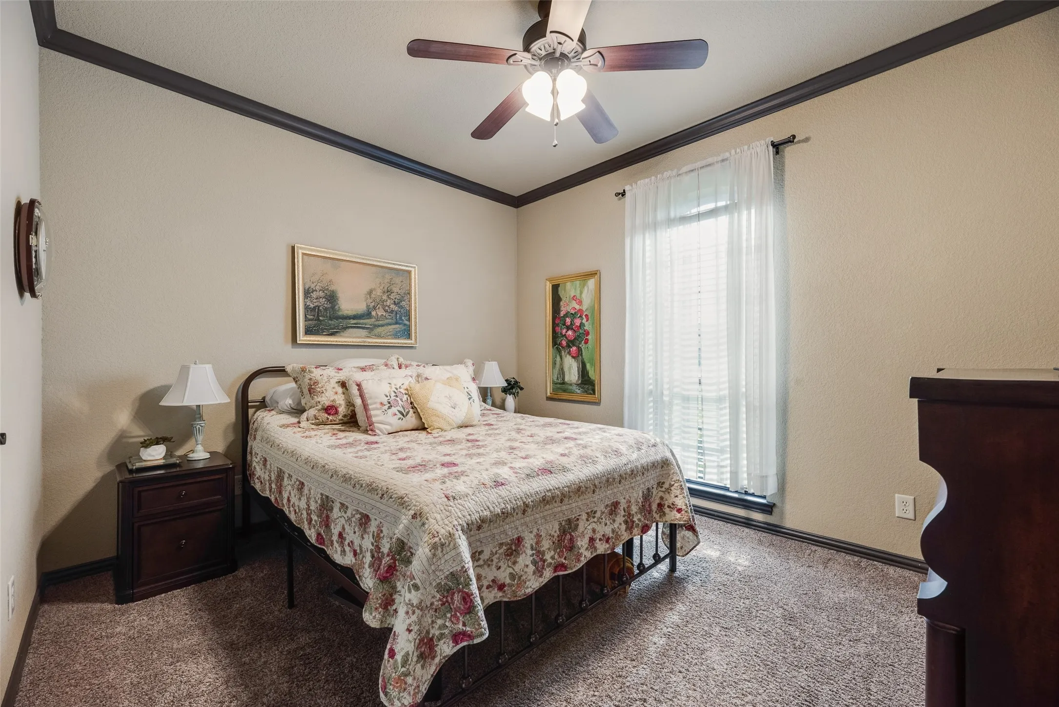 Carpeted room featuring a ceiling fan with integrated lighting, dark crown molding, and a window with blinds and sheer curtains
