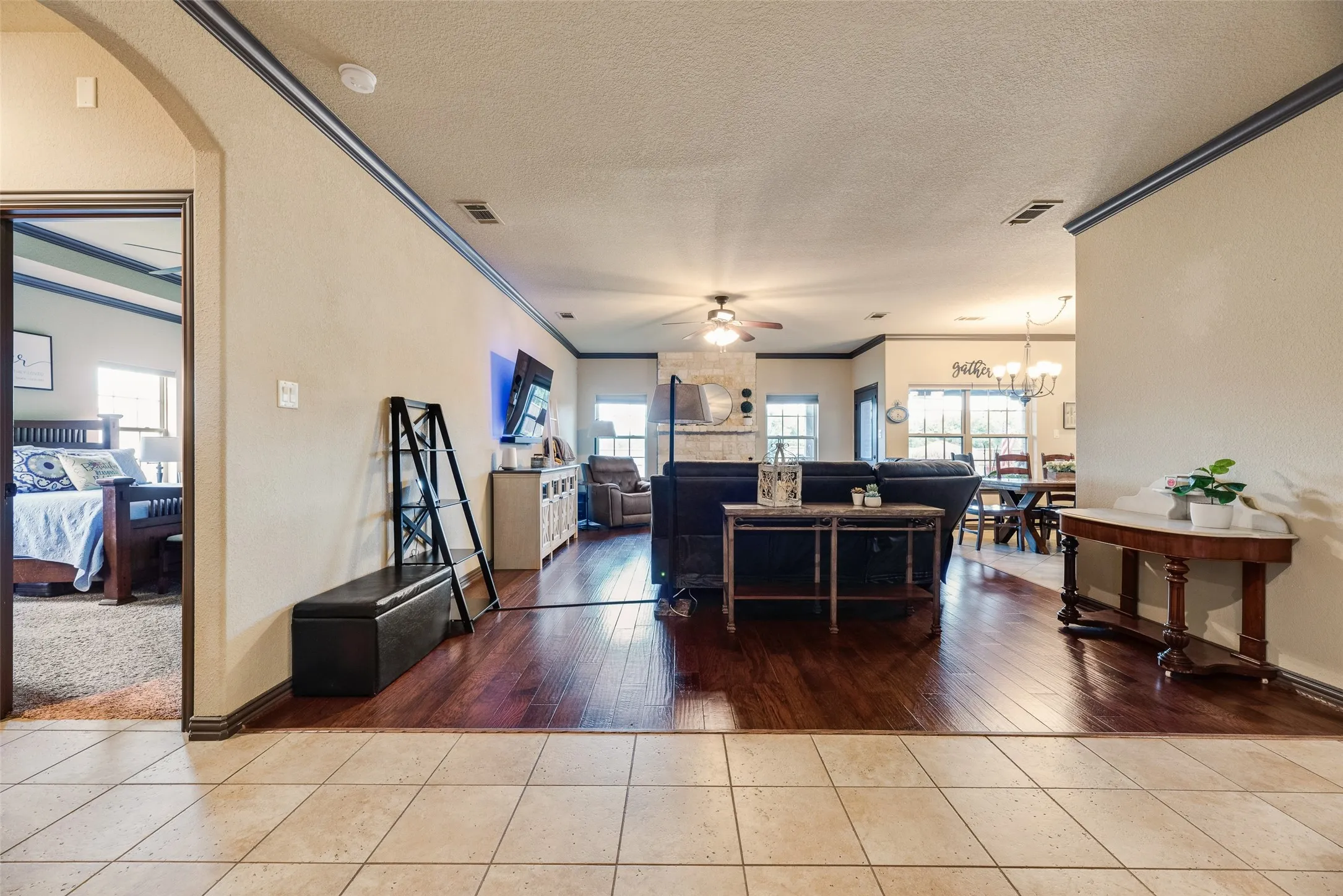 Open-concept living area featuring wood-finish flooring, light-toned wall paint, and dark crown molding
