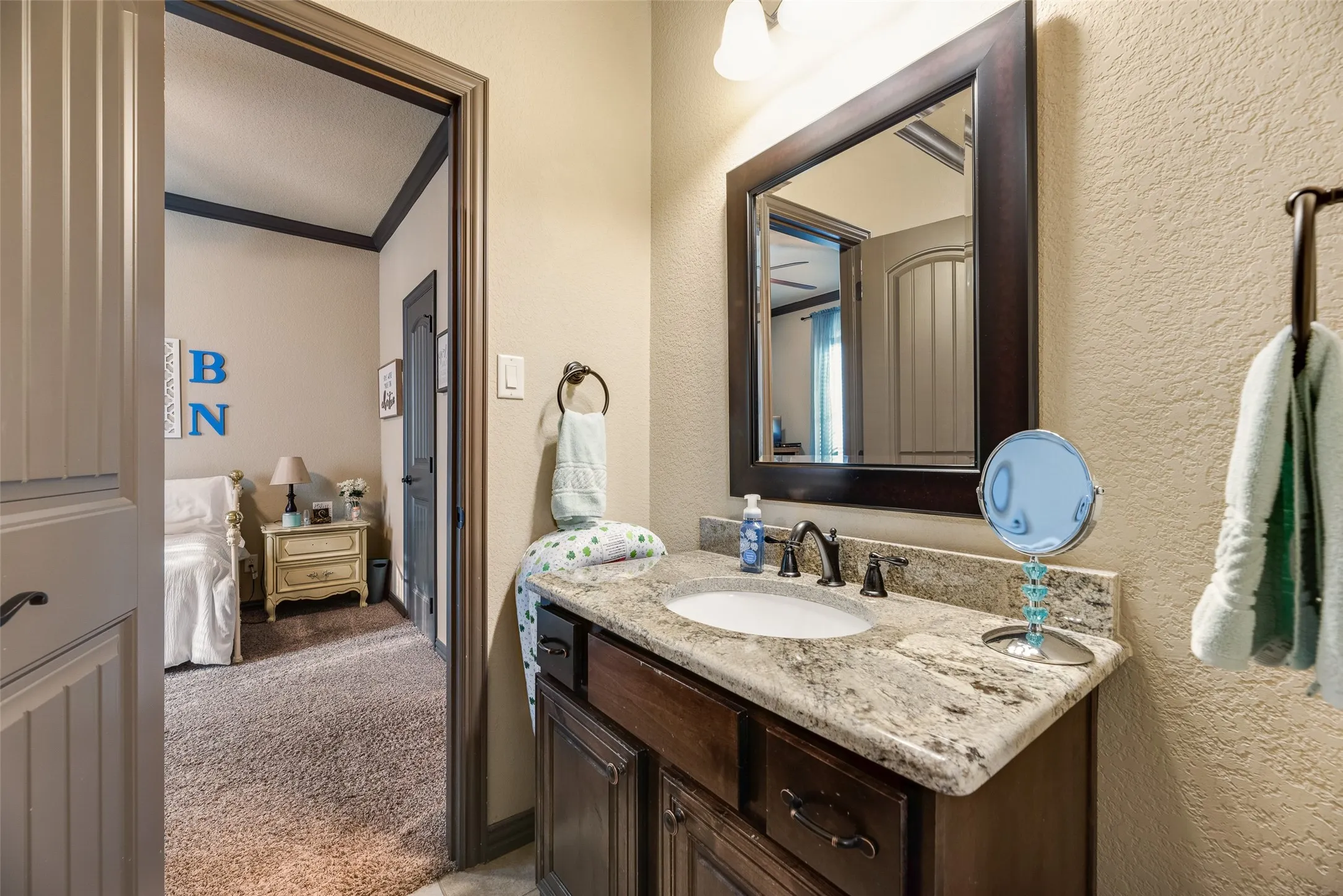 Bathroom vanity featuring a light-toned granite countertop, undermount sink, and dark bronze-finish fixtures
