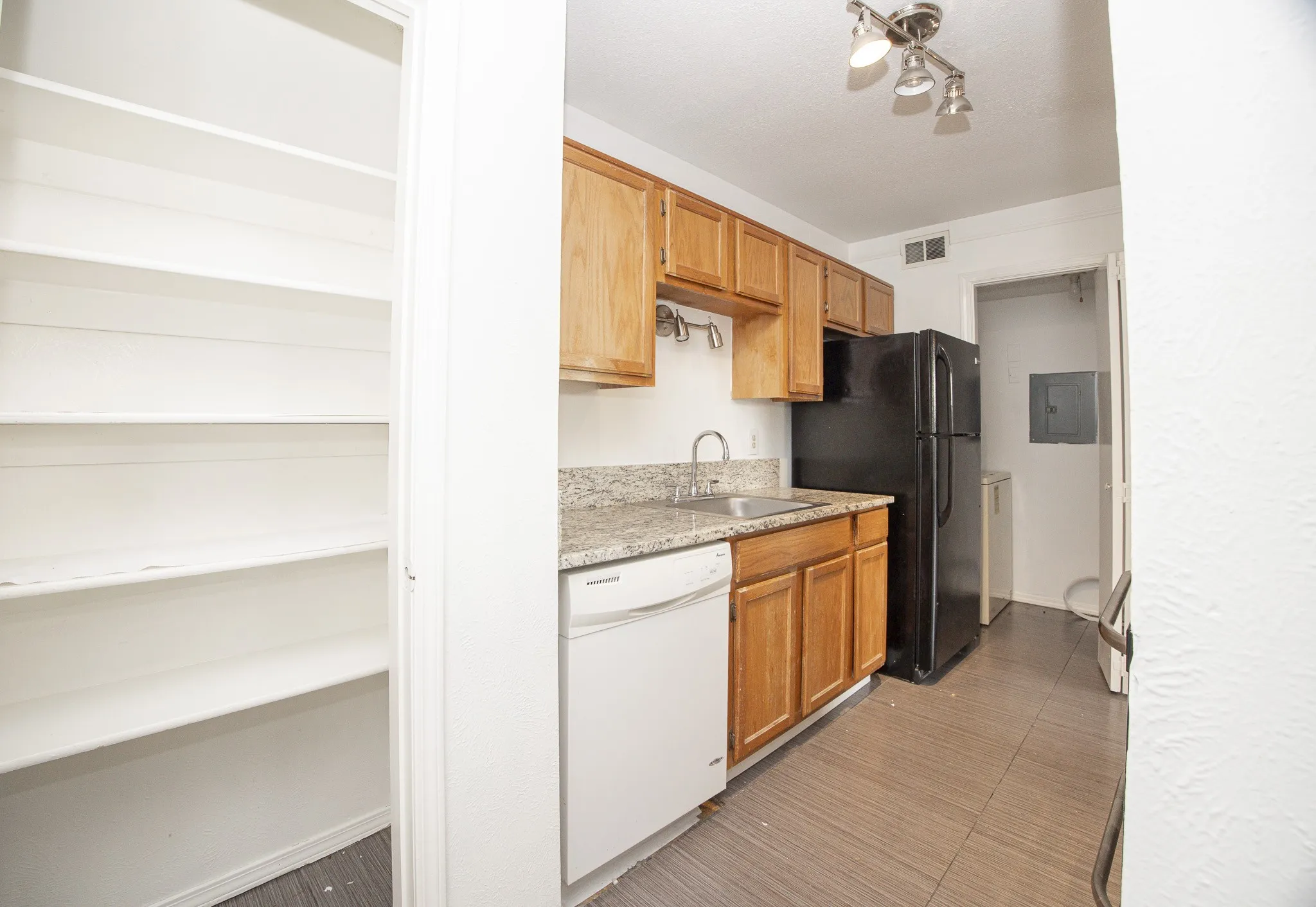 Kitchen featuring granite-style countertops, wood-finish cabinetry, tile flooring, and a built-in dishwasher