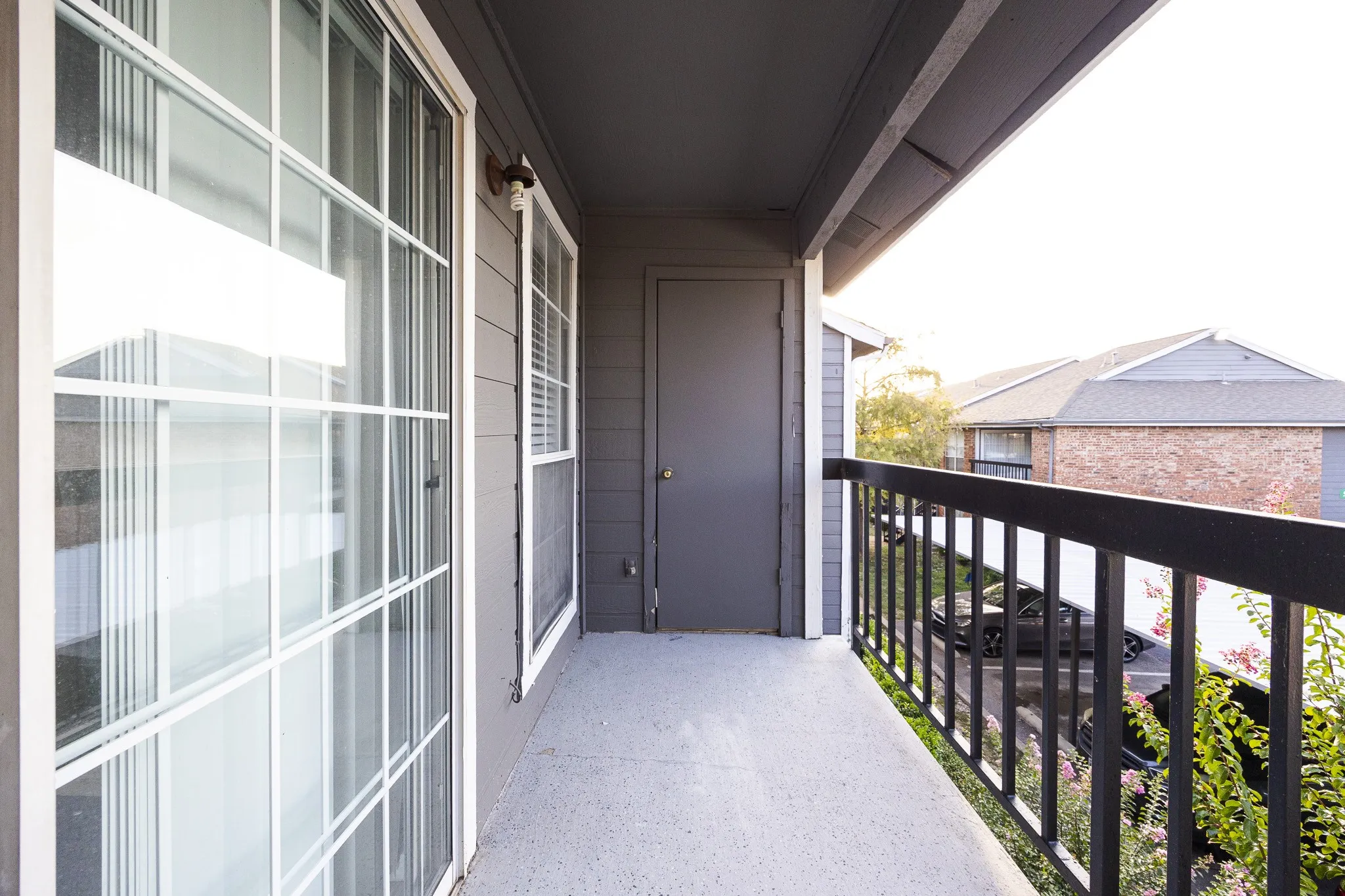 Private balcony featuring a dark grey exterior, white frame sliding glass door, and black metal railing