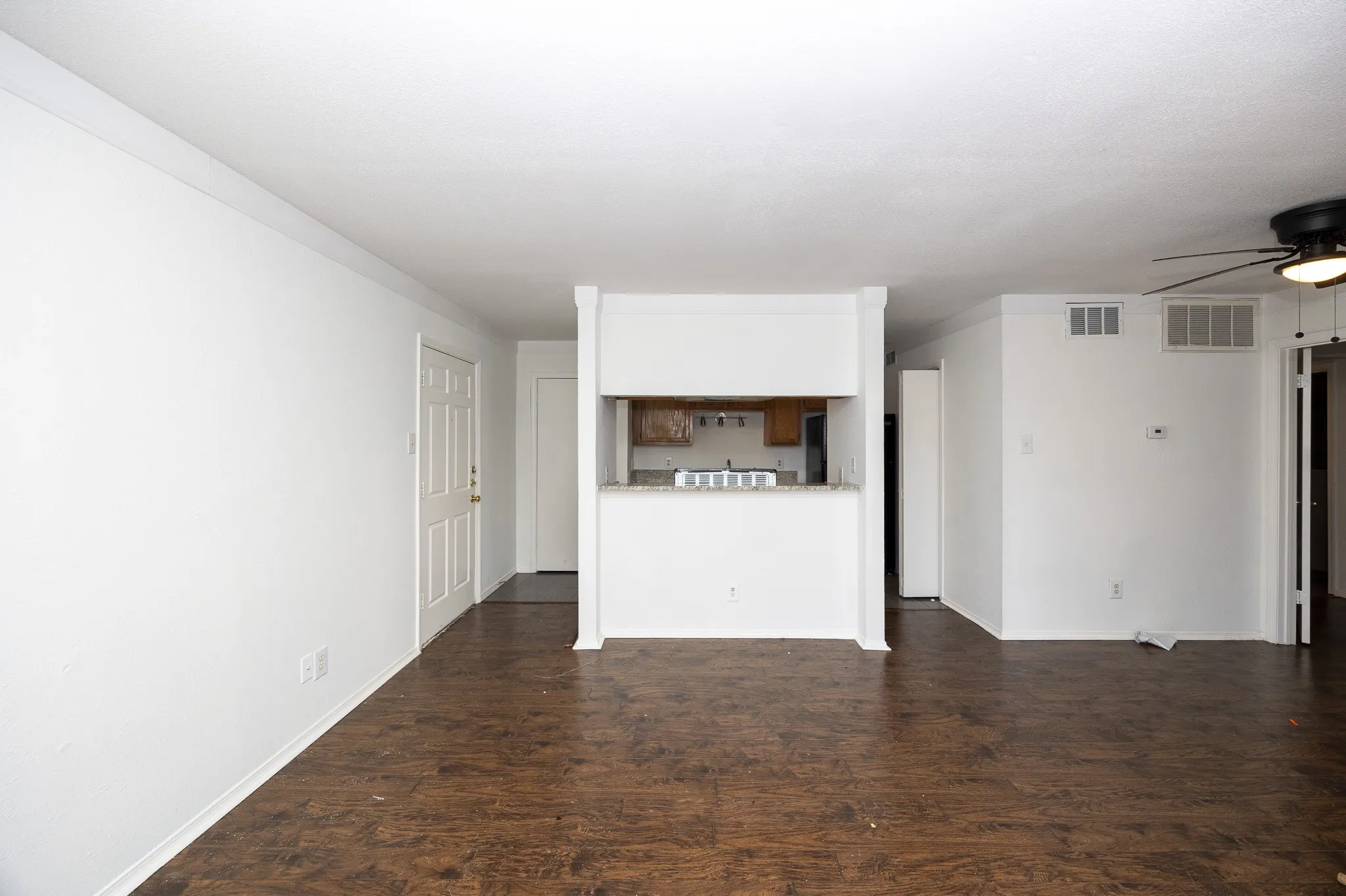 Wood-finish flooring throughout, white painted walls, and a built-in breakfast bar with a light-toned countertop