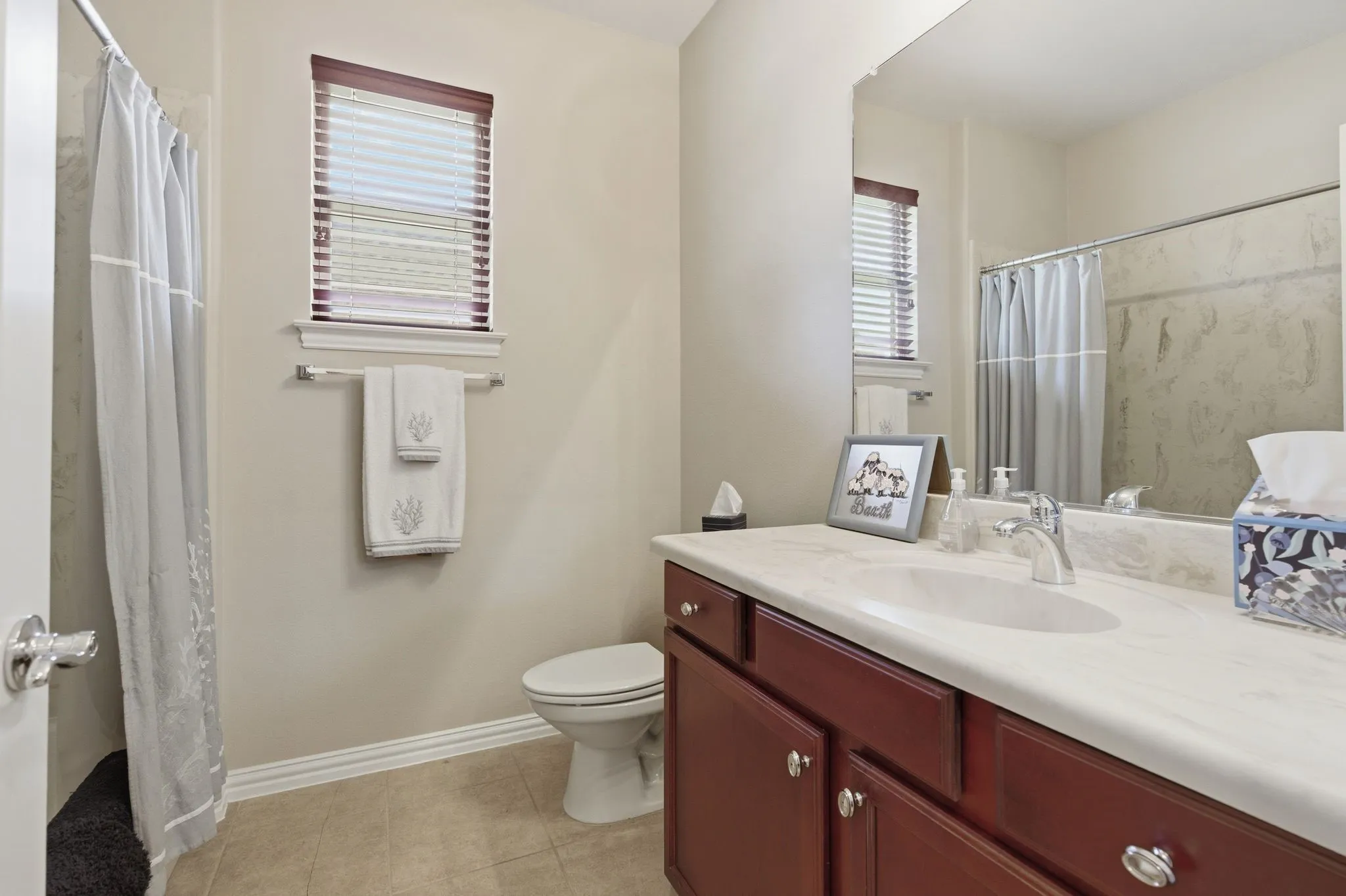 Bathroom featuring a wood-finish vanity with an integrated sink and light-toned countertop