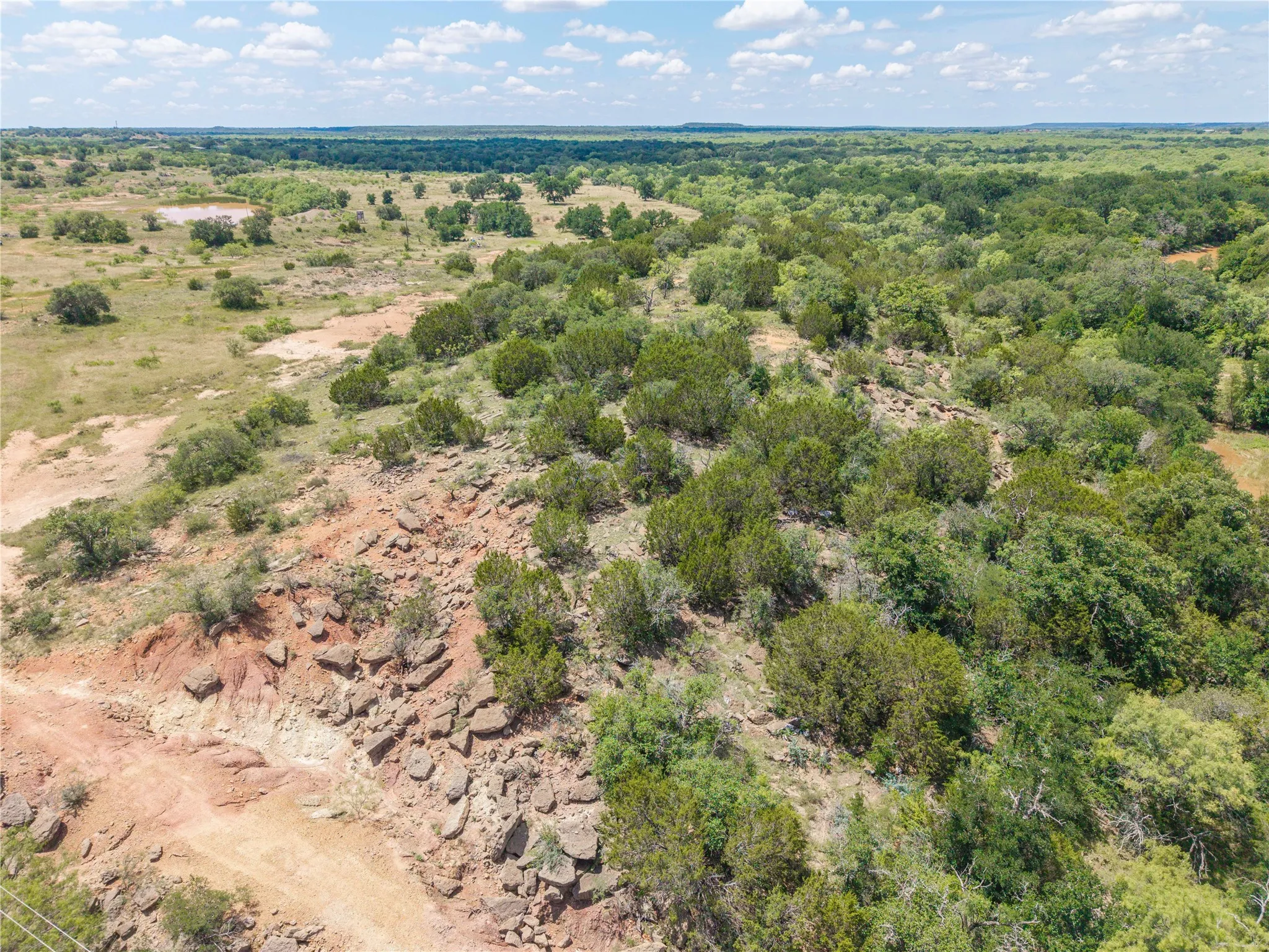 Expansive land featuring varied terrain, including areas of scattered trees and open fields