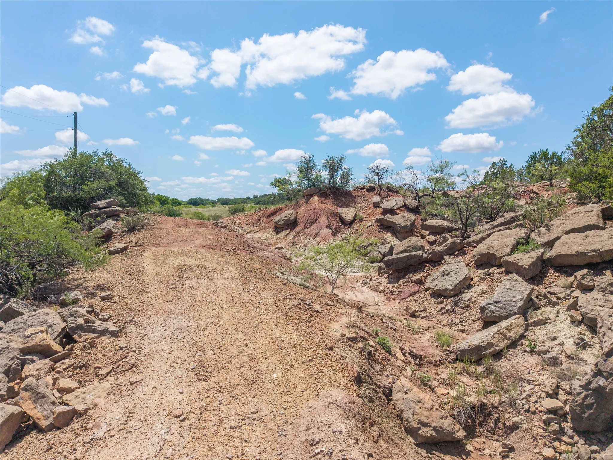 Unpaved path bordered by natural rock formations and varied vegetation