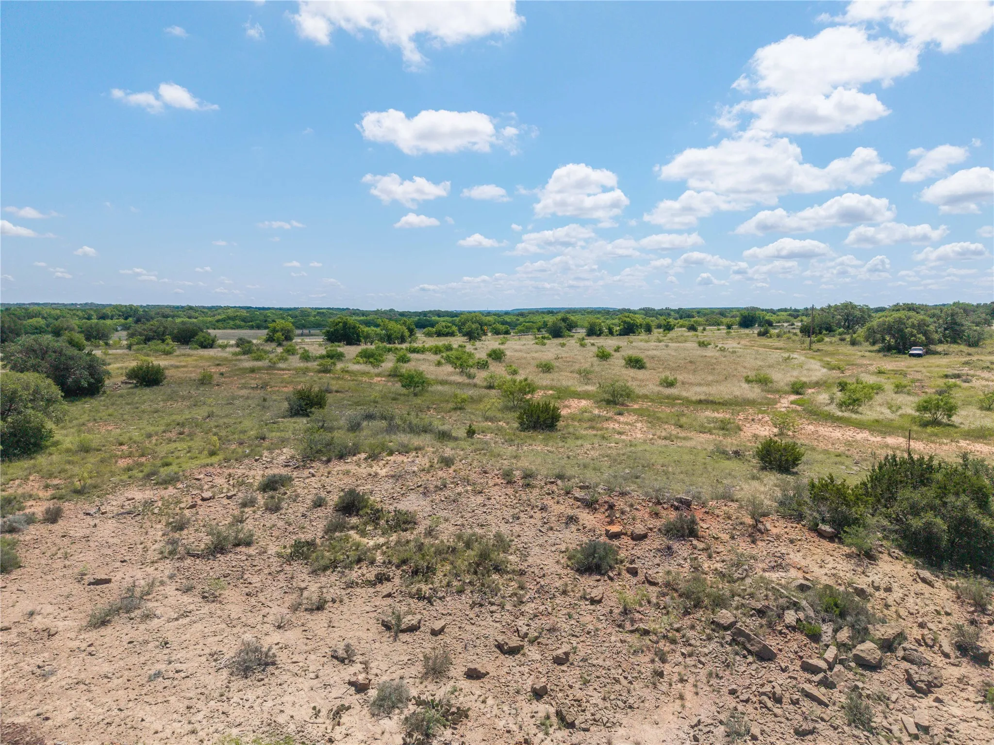 Expansive open land featuring varied topography, scattered mature trees, and natural vegetation
