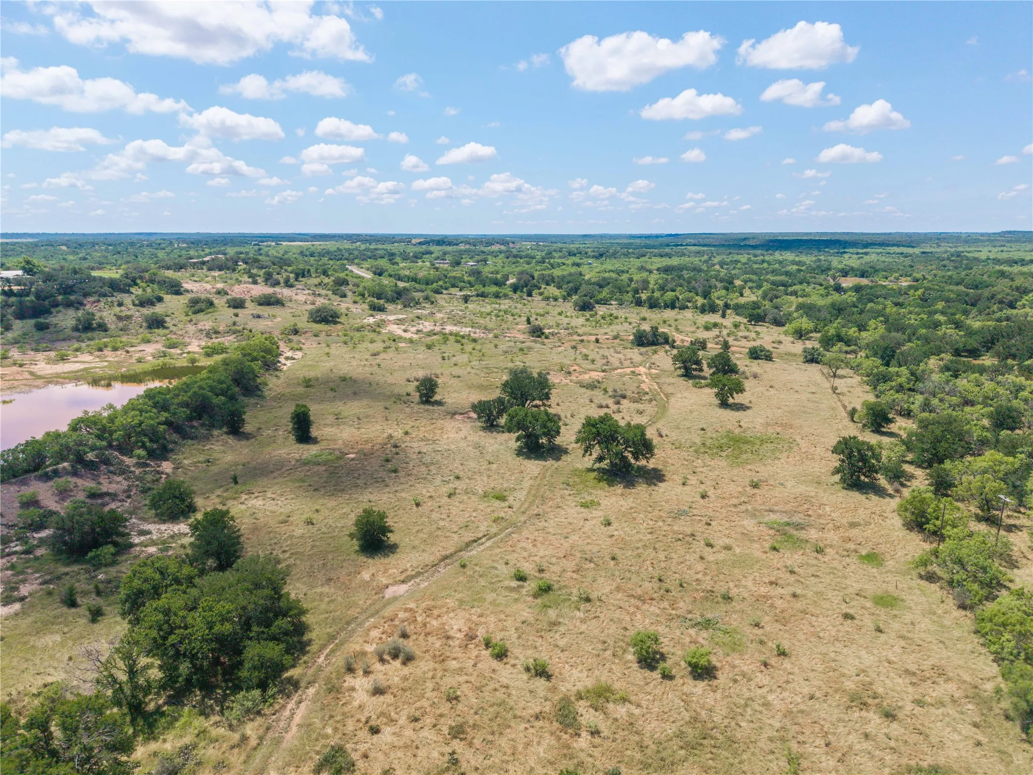 Expansive acreage featuring a natural pond, scattered mature trees, and varying topography