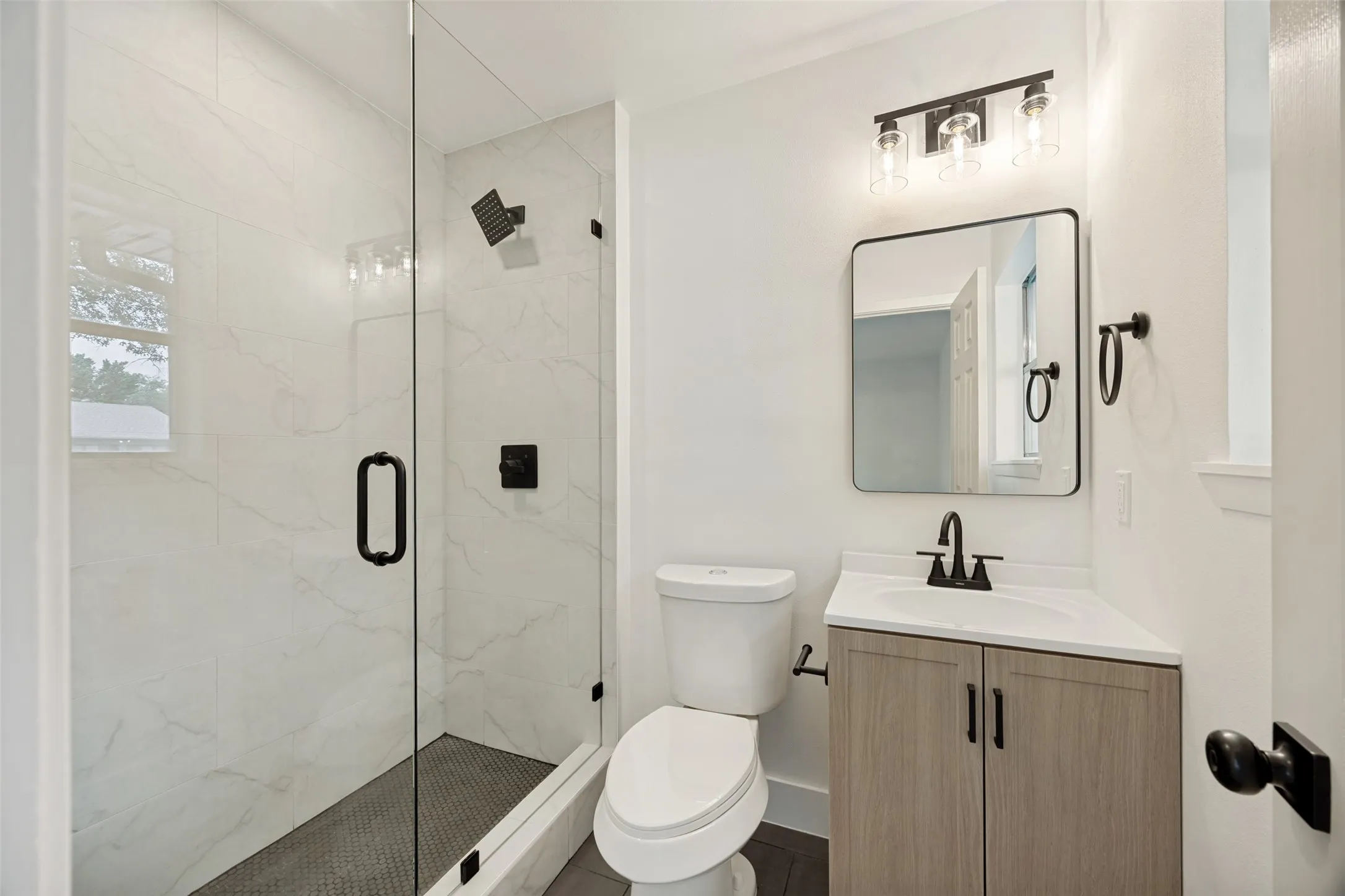 Walk-in shower featuring a frameless glass enclosure and white tiled walls