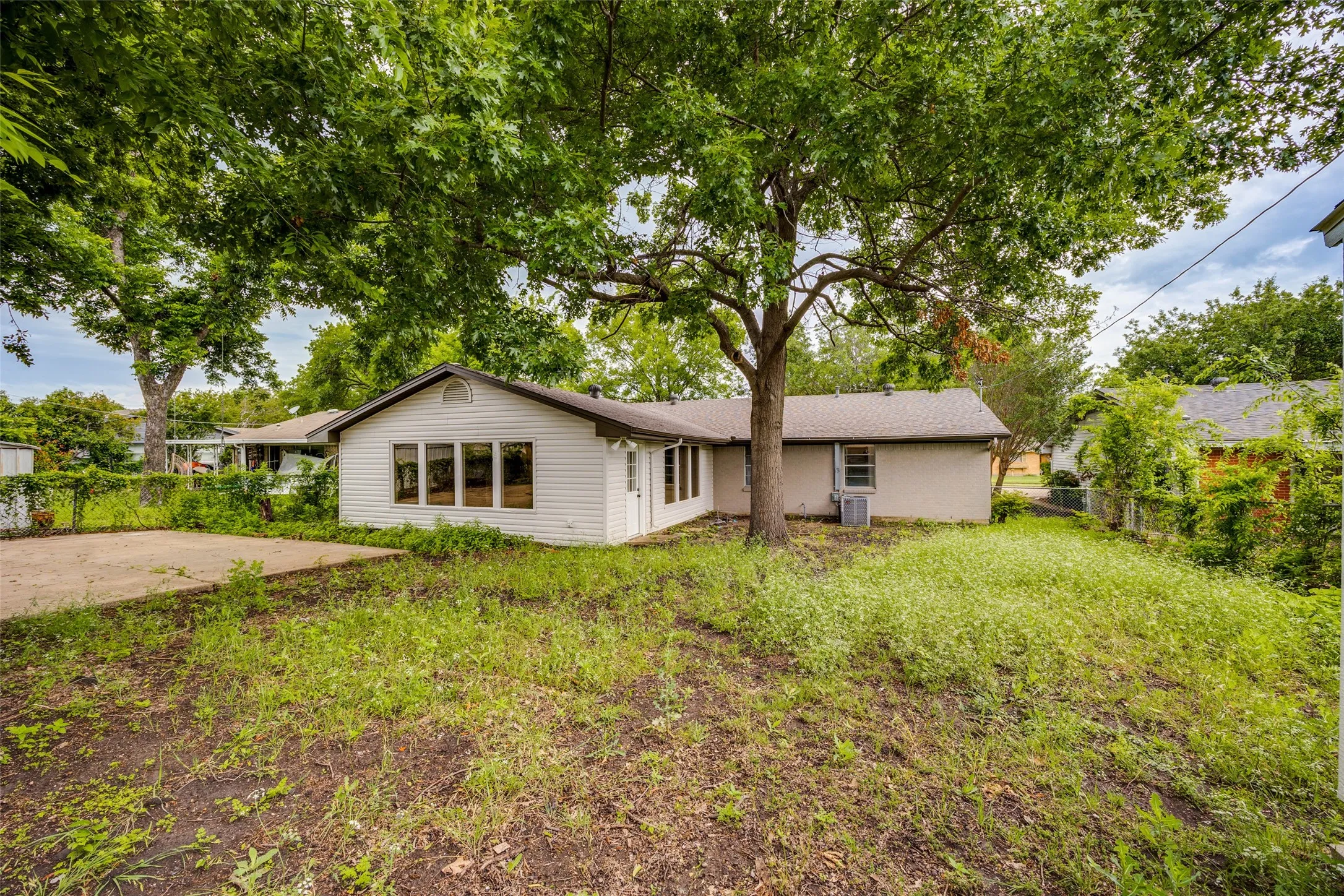 Expansive rear yard featuring mature trees and a concrete patio area