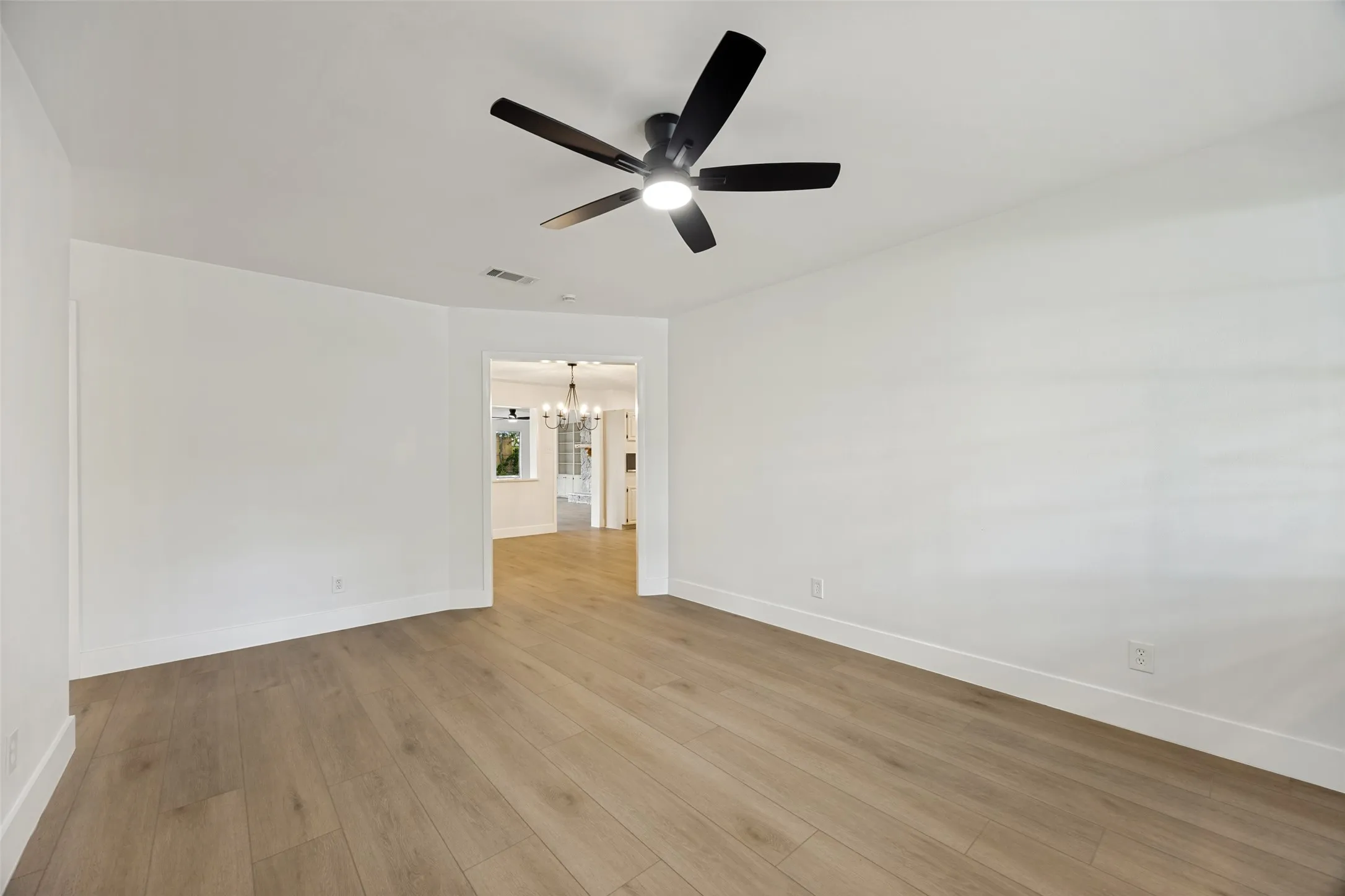 Spacious room featuring wood-finish flooring and a modern ceiling fan with integrated lighting