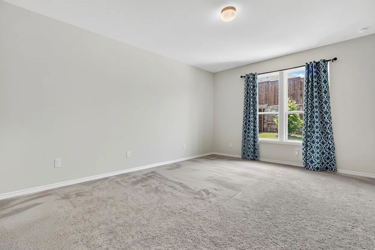 Spacious room featuring light gray carpeting, neutral wall paint, and white baseboards