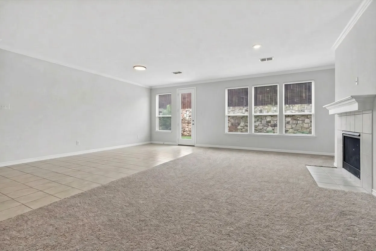 Spacious living area featuring neutral carpet flooring, recessed ceiling lighting, and multiple large windows with custom cabinetry