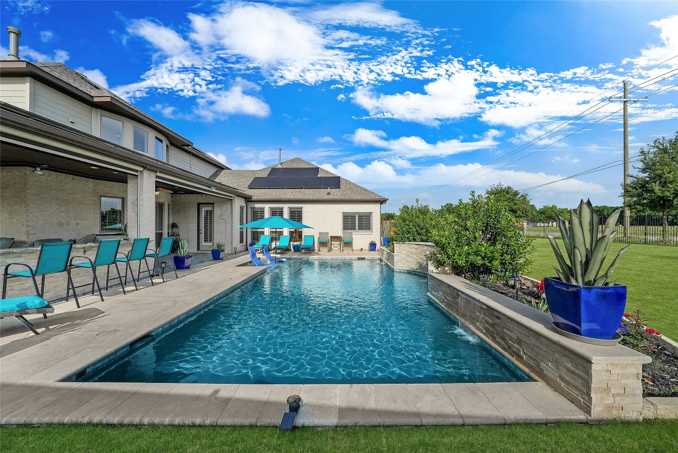 In-ground rectangular swimming pool featuring a stone-clad water feature