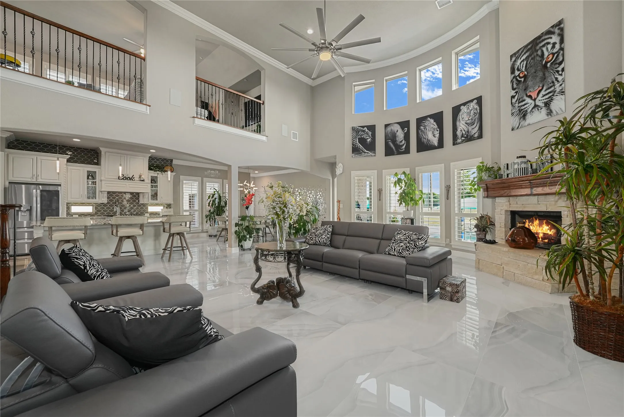 Spacious living area featuring high ceilings, white tile flooring, and a stone-clad fireplace