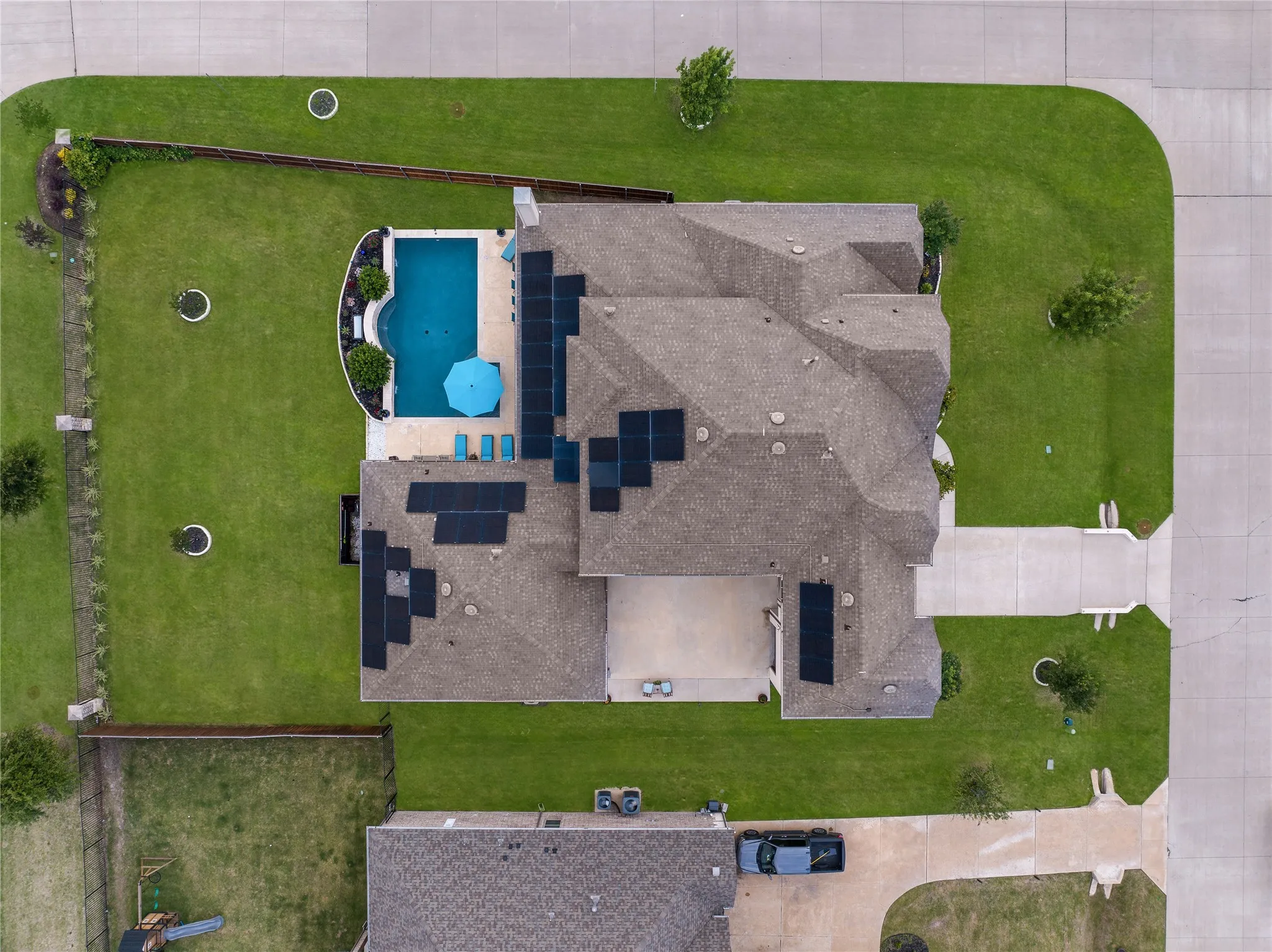 Aerial perspective showcasing a property with a private pool, extensive solar panel array, and a spacious green lawn