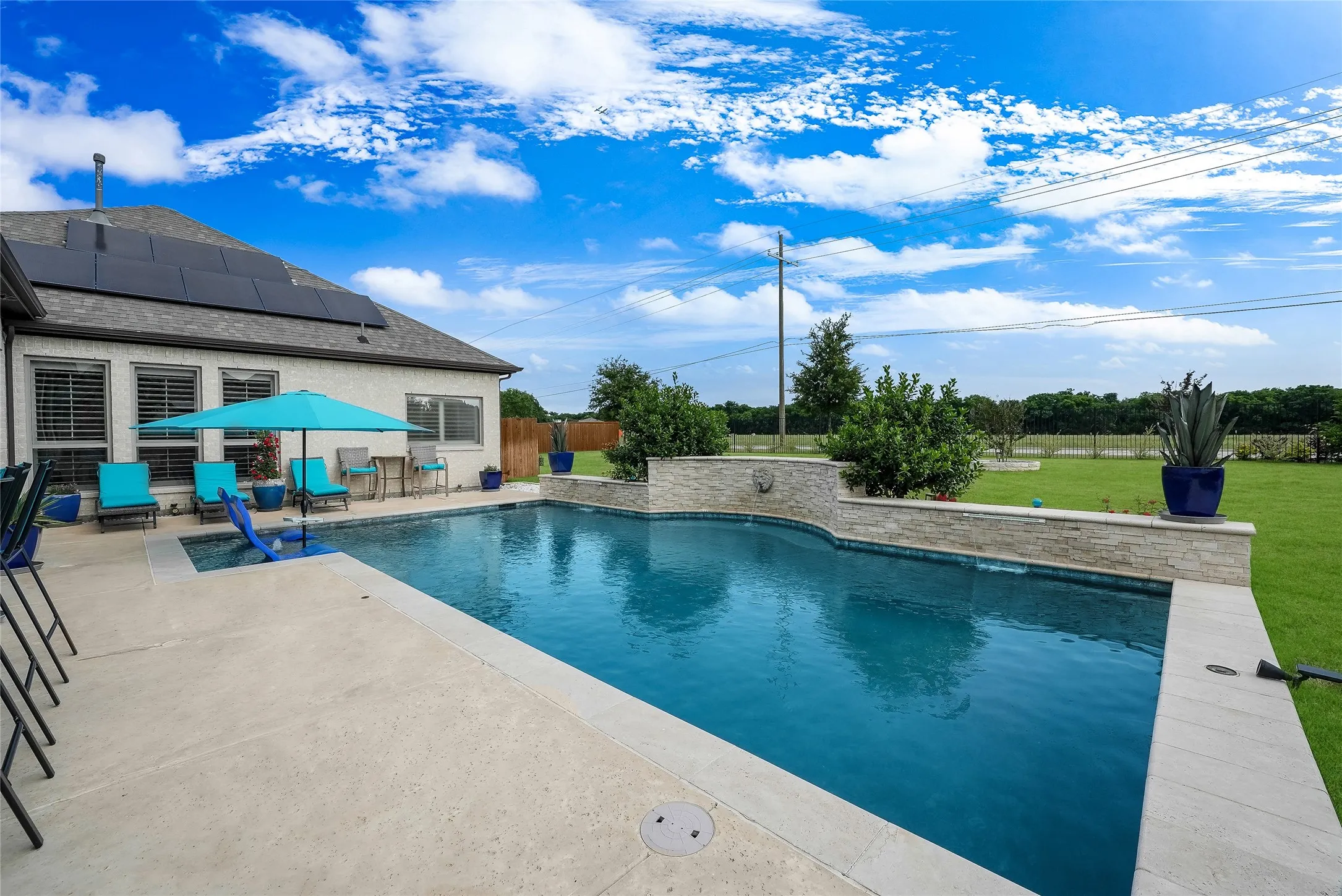 In-ground swimming pool with integrated spa and stone-clad retaining wall