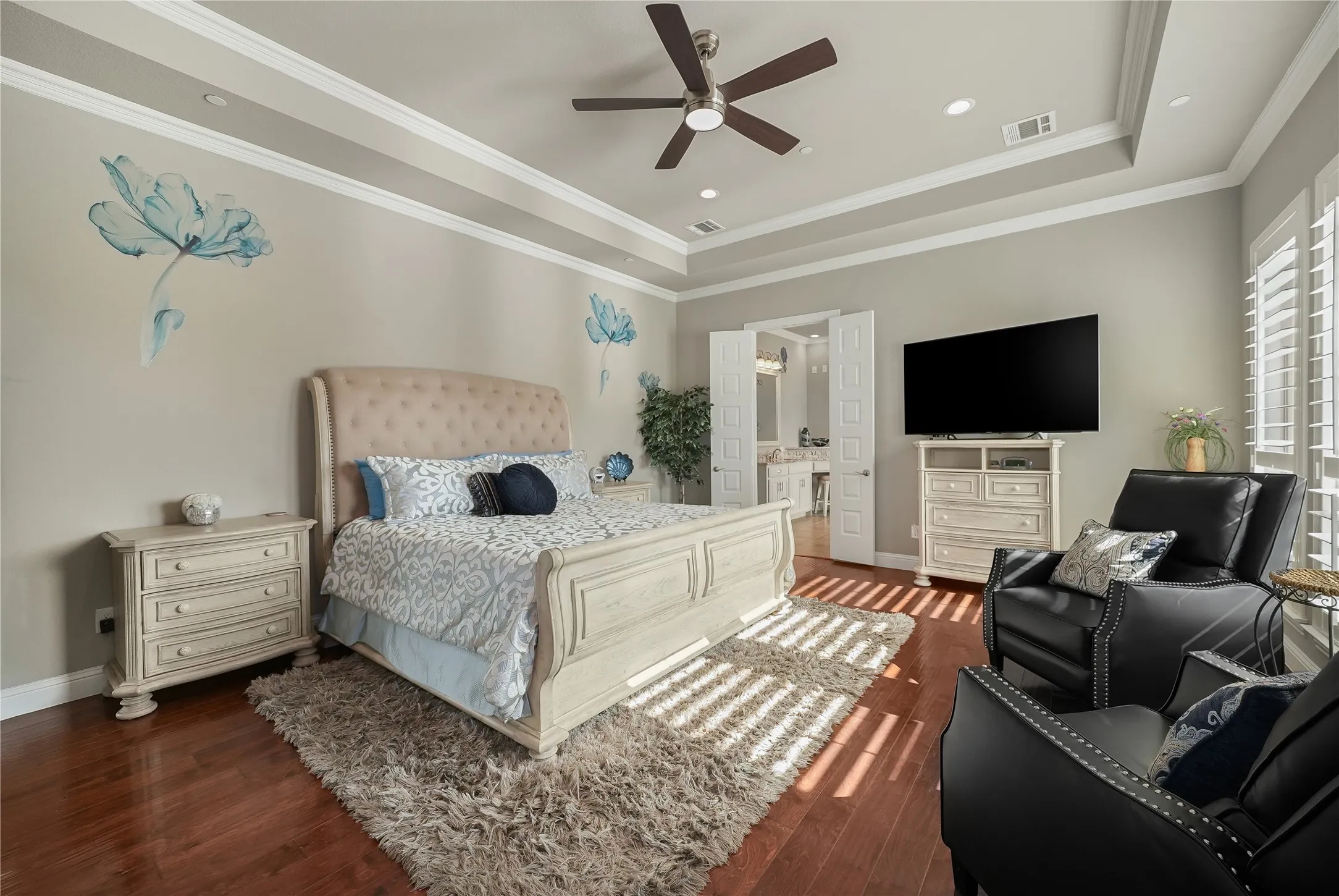 Spacious room featuring rich wood-finish flooring, a tray ceiling with crown molding, and recessed lighting
