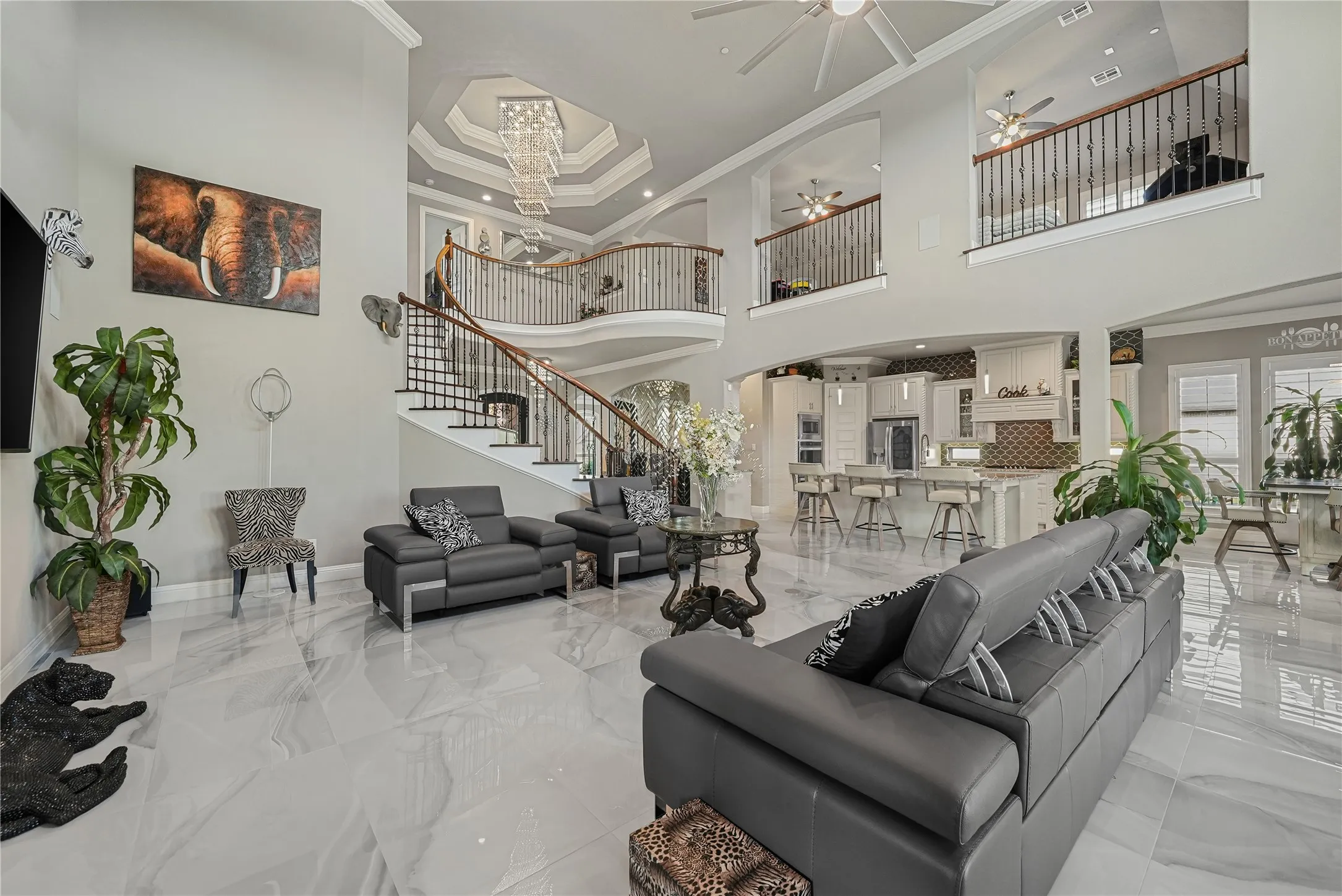 Grand living area featuring a two-story ceiling, a sweeping staircase with dark wood handrails and wrought iron balusters, and expansive light-toned tile flooring
