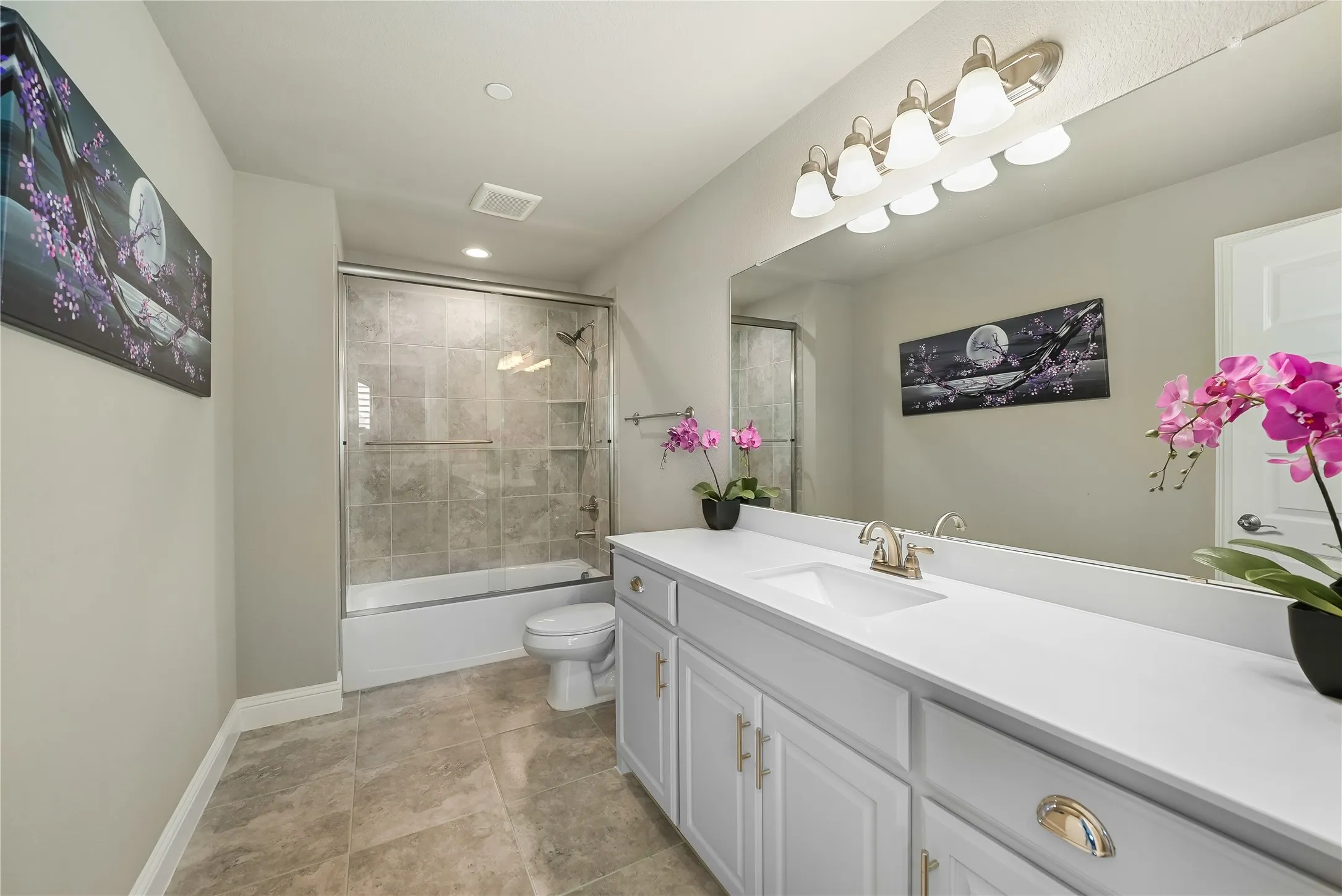 Bathroom featuring a spacious vanity with an integrated sink, broad mirror, and contemporary light fixture